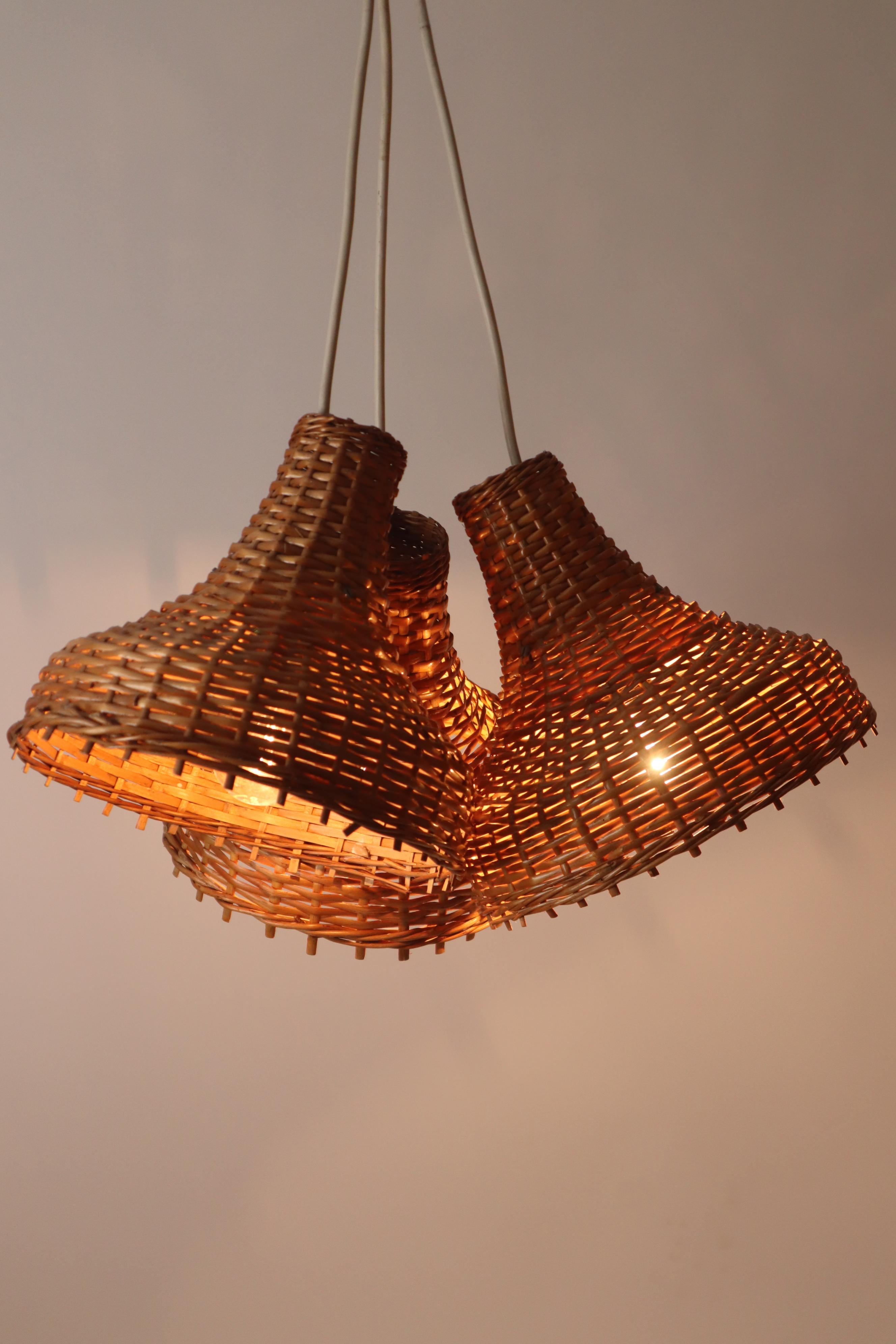 Questo raro set di tre lampade a sospensione, realizzate a mano in rattan, ti incanterà. Realizzate negli anni '60 nella Germania dell'Est, le luci sono state intrecciate a mano con un'abile maestria. Nel corso dei decenni, le luci hanno acquisito