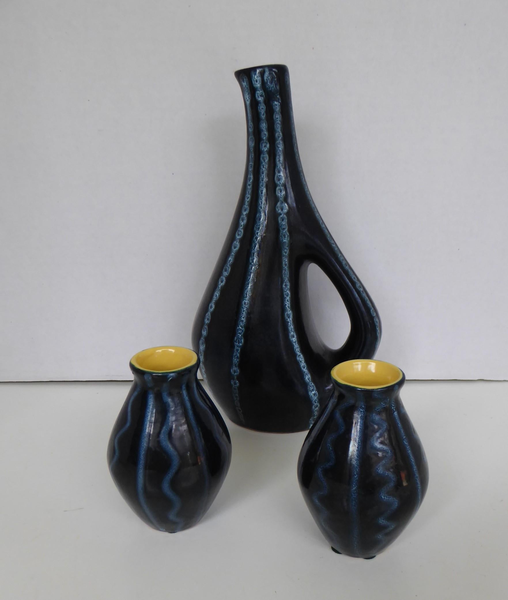 A set of three midcentury ceramic vases by Tofej, a Hungarian pottery maker. These date from the 1950s and the set is comprised of a tall vase with handle and two small bulbous vases. The decoration on all three is of incised blue lines and