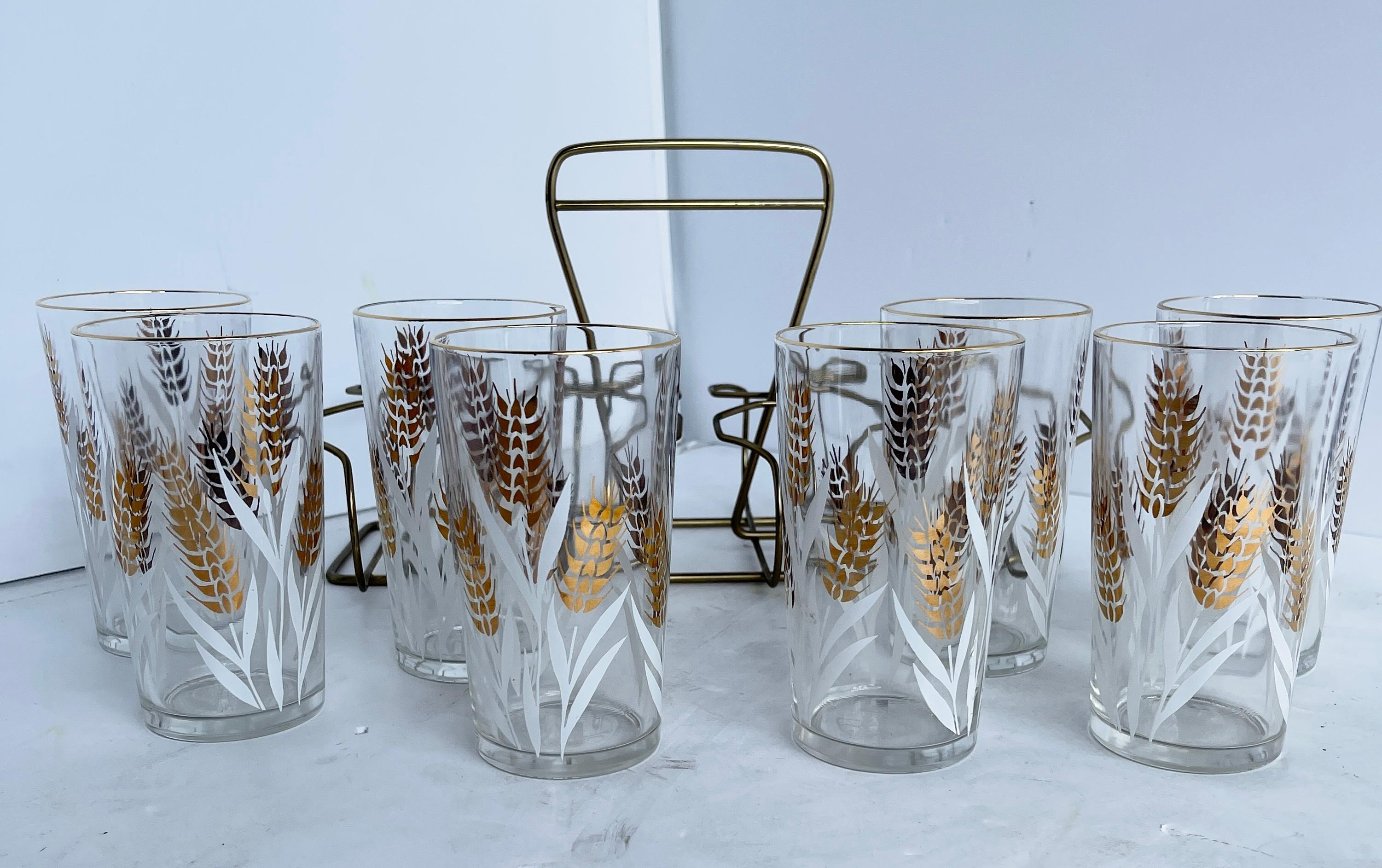 Set of eight Mid-Century Modern highball glass set with brass caddy. 
Look at this Classic bar set with it's glowing gold overlay on the rim and heavily decorated gold and white wheat sheaf pattern! Complete with caddy ready to carry to your
