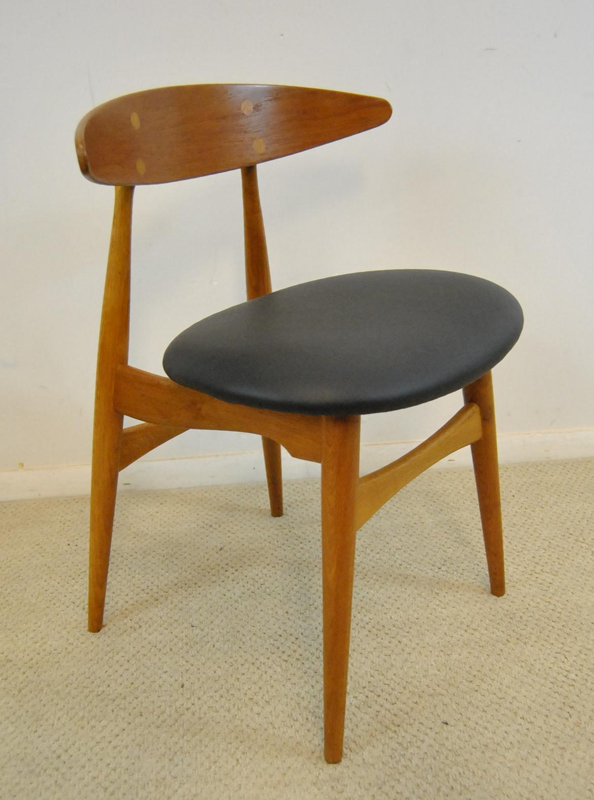 A great set of four dining chairs designed by Hans Wegner. This is the iconic Model CH33 designed for Carl Hansen & Son, Denmark. Clearly marked as pictured. Black leather seats in great condition.