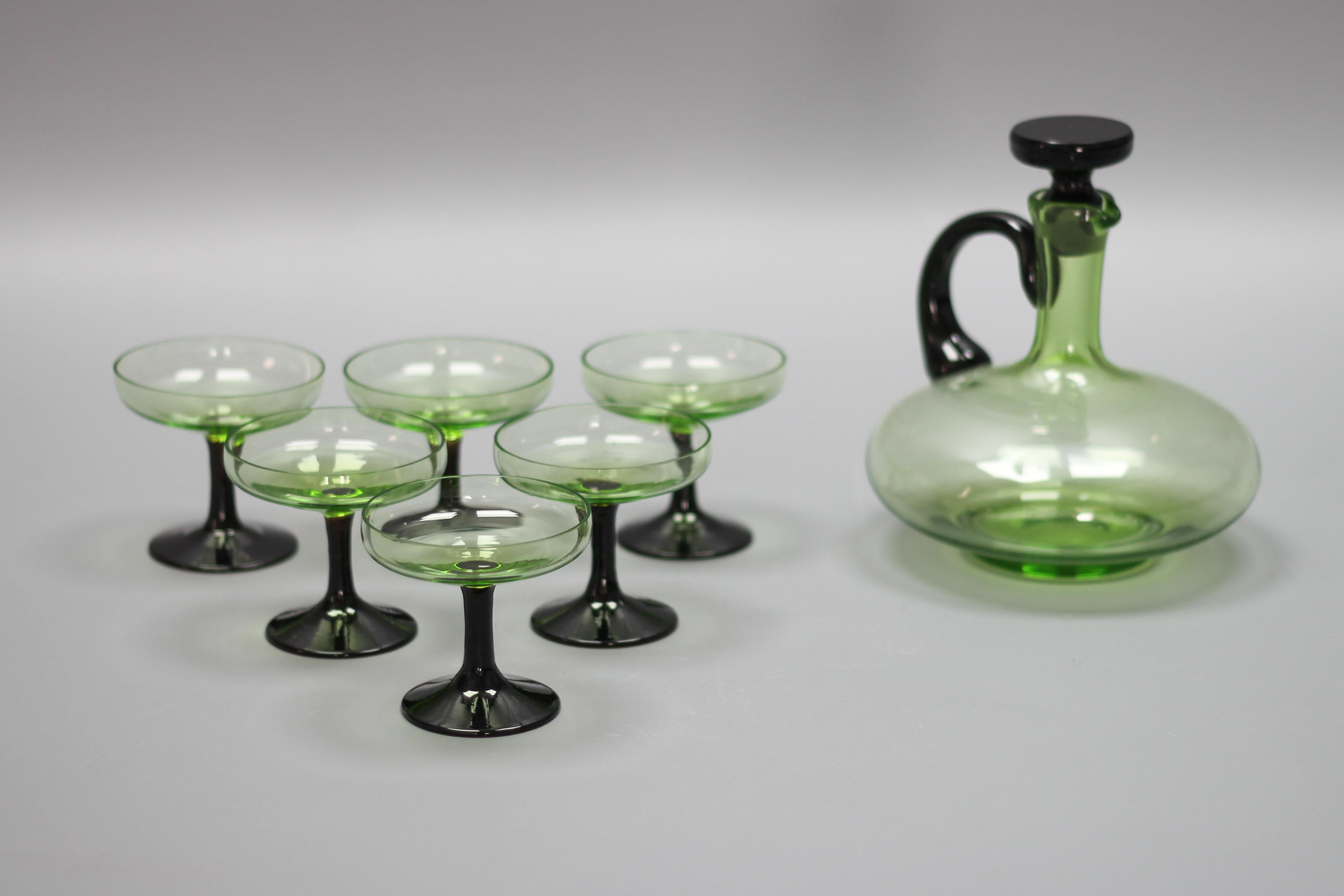 Mid-Century Modern set of green and black glass decanter and six glasses, Germany, circa the 1950s.
This adorable vintage set features six light green glasses with black stems and a beautifully shaped light green decanter with a black glass stopper