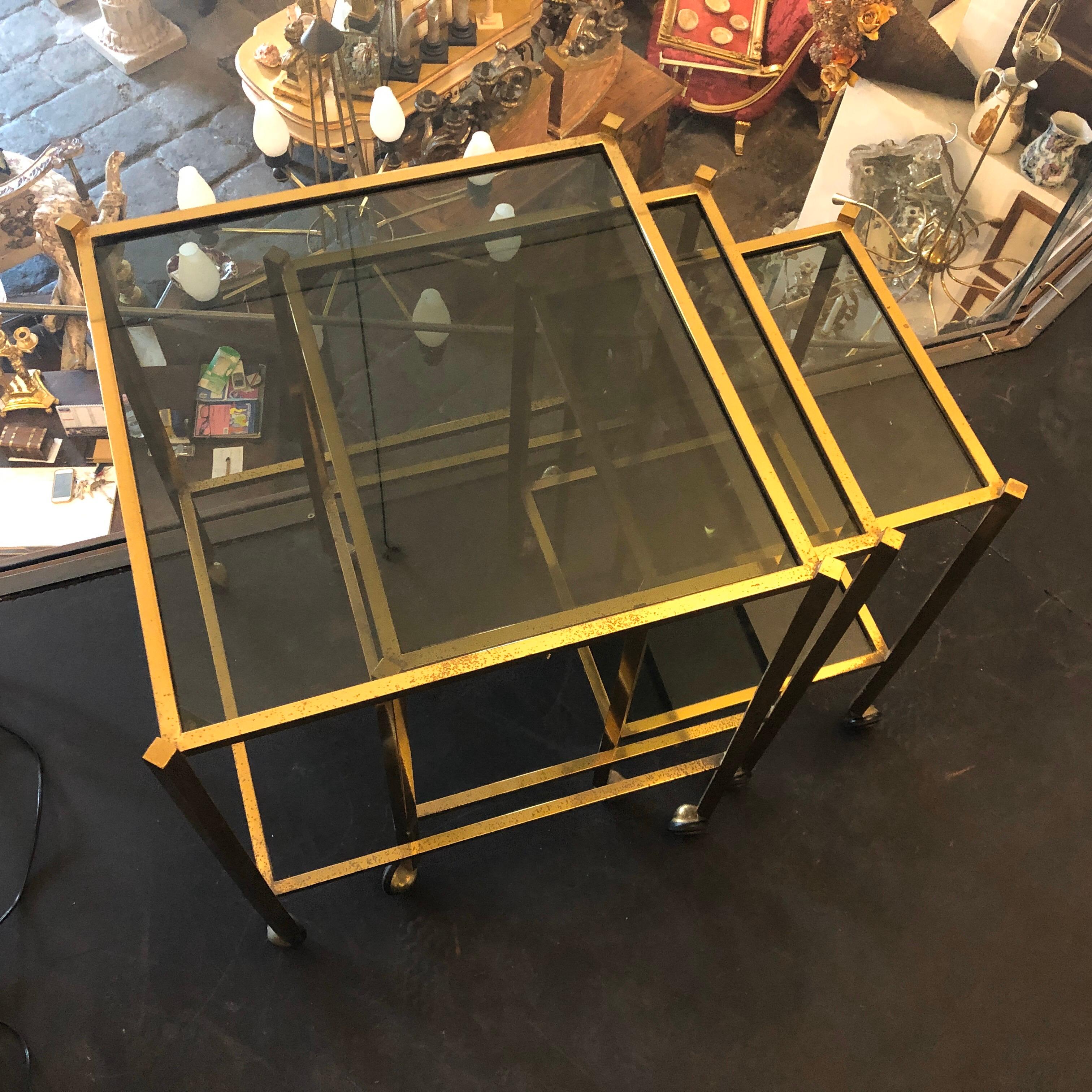 Three Italians nesting tables, brass in original patina and glasses in perfect conditions, they are on wheels.