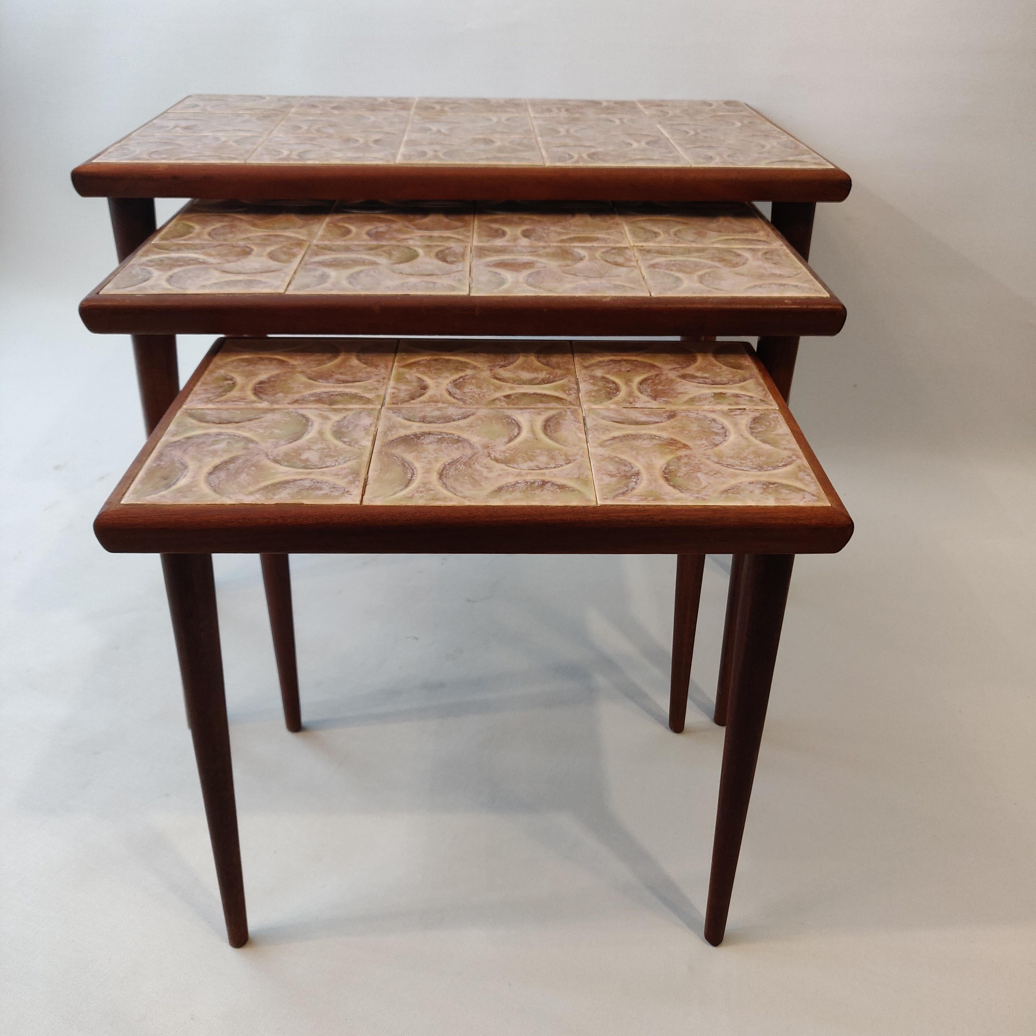 Satz von drei dänischen Nisttischen aus der Mitte des Jahrhunderts, 1960er Jahre.
Das Gestell der Tische ist aus Teakholz gefertigt, das dem Rahmen seine schöne tiefbraune Farbe verleiht. Die Tischplatte ist mit Keramikfliesen in verschiedenen