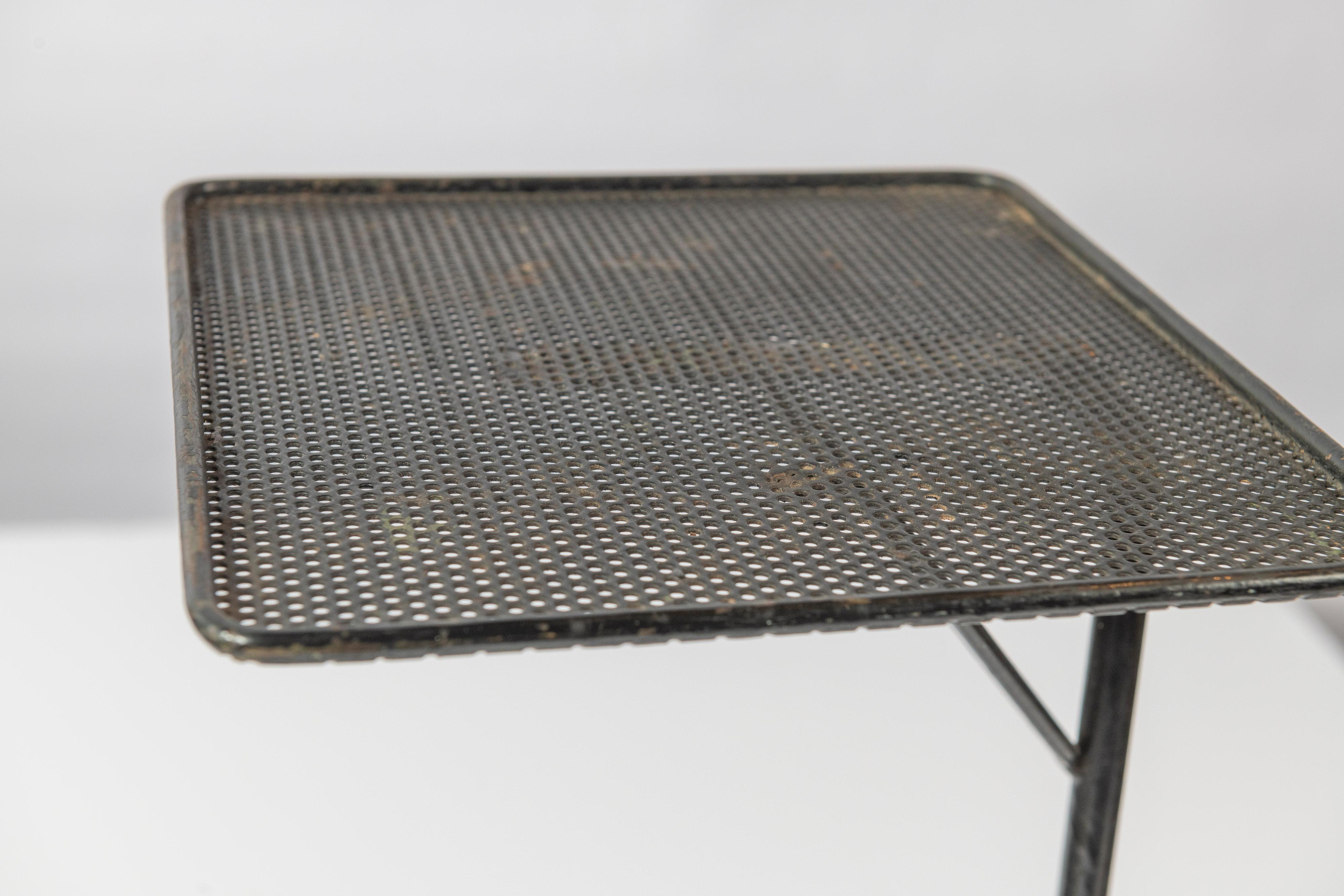 This vintage Mid-Century Modern side or telephone table in perforated metal with shelf is quite functional. In good condition, this small piece can serve as a side table, plant stand, telephone stand, magazine/book storage, bedside table and beyond.