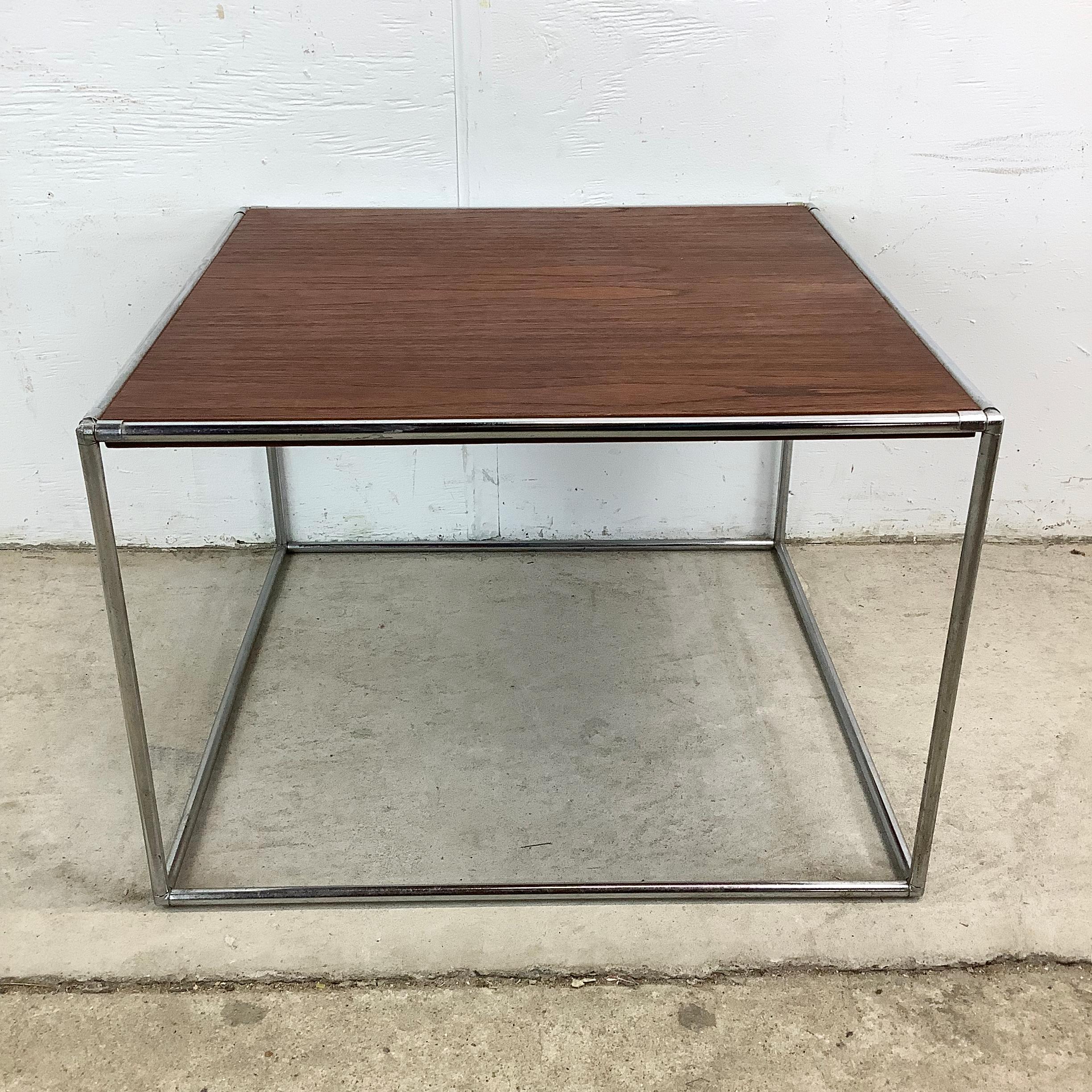 This vintage mid-century chrome and walnut side table showcases the best of classic modernism with its simple cube frame and warm wood surface. The design is refreshingly straightforward—an open square of chrome supports a walnut top that has aged