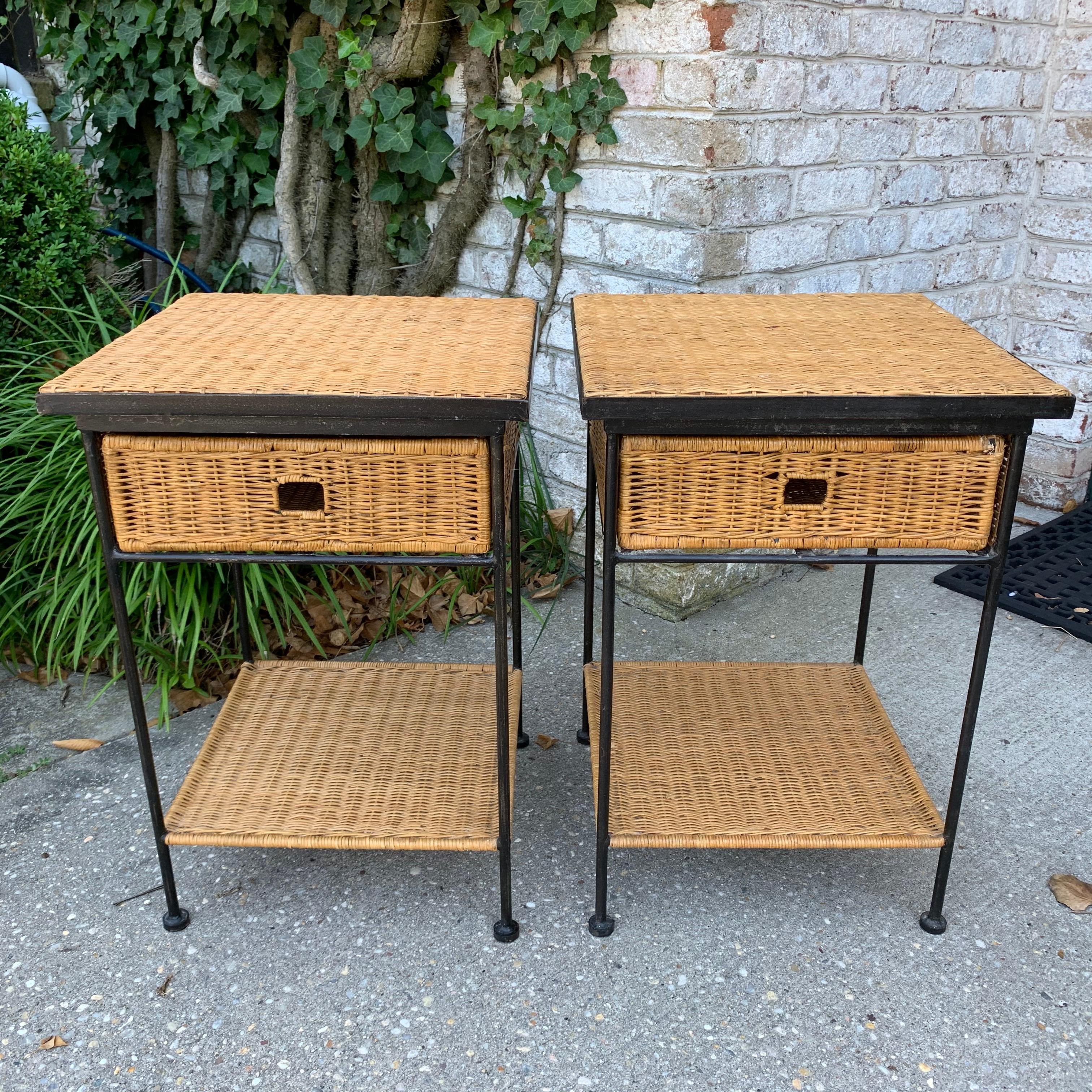 Vintage side tables in black metal frame and wicker. Very well constructed with single full wicker drawer per table and lower shelf. Very similar to work of Paul McCobb and Arthur Umanoff.
    