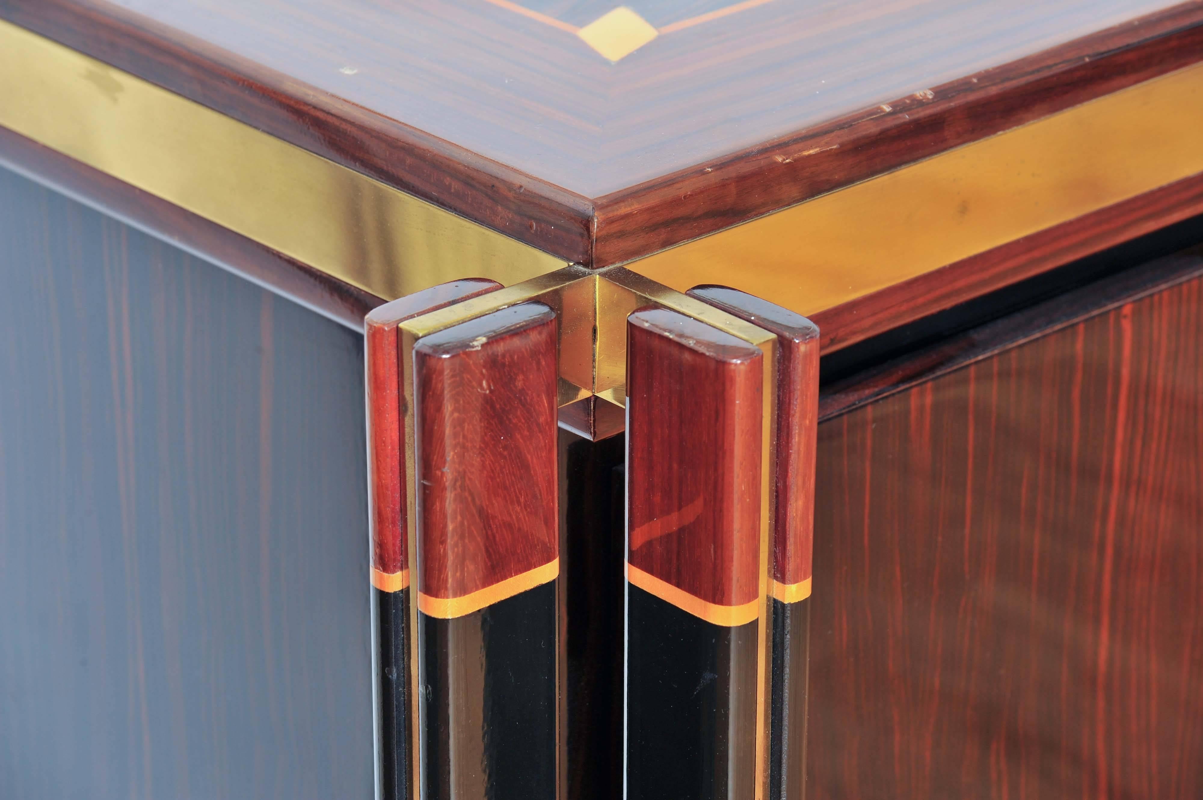 Madagascar wood sideboard is decorated with patterns of contrasting veneers and light fruit wood inlays and brass lines. The credenza is edged with brass borders, emphasizing its geometric lines with the structure in wood and brass in the four
