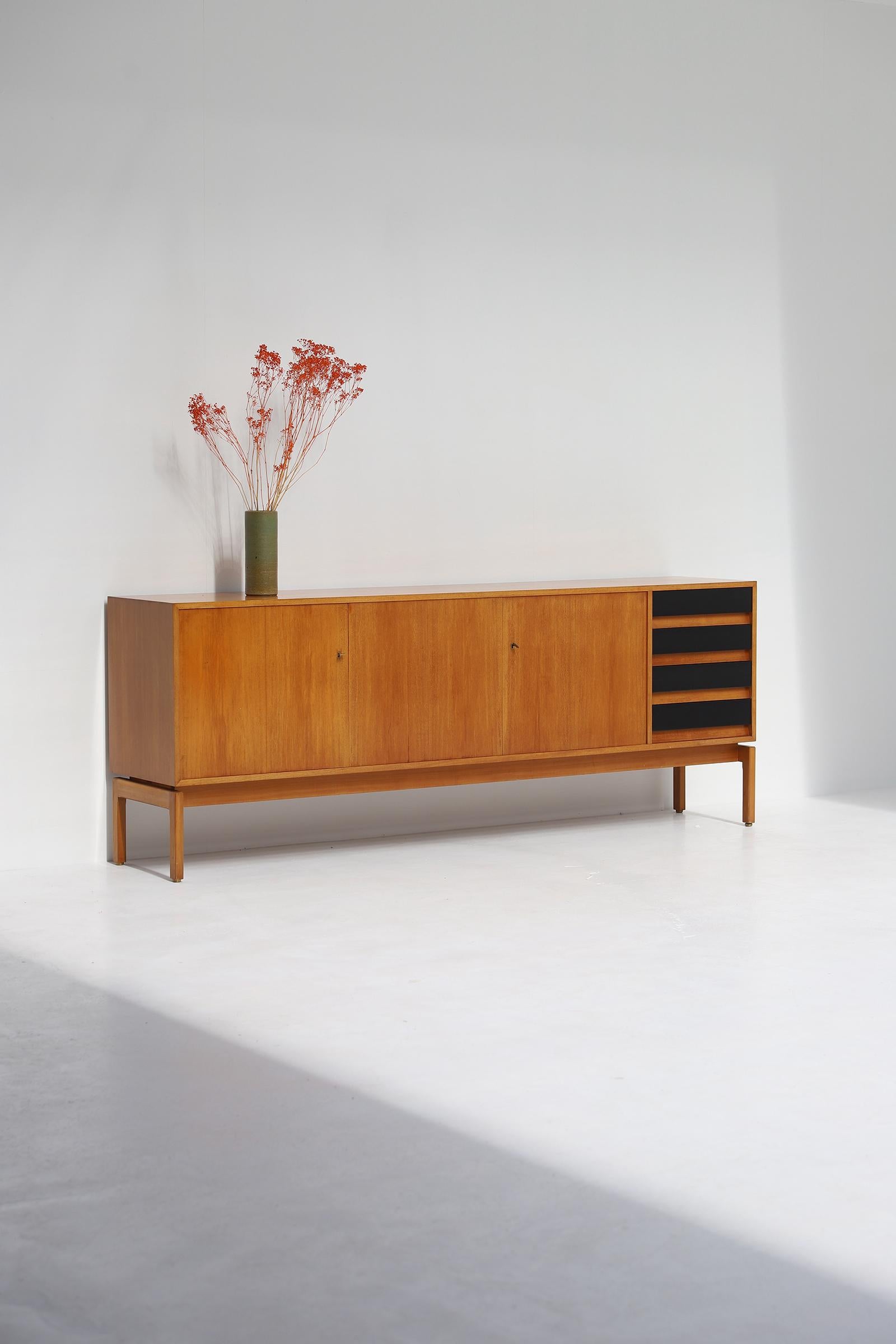 Jos De Mey sideboard manufactured in the 1960s by Van den Berghe Pauvers Gent, Belgium. The sideboard is made in a dark honey colored wood detailed with a brass key and black lacquered drawers. Behind the 3 doors there is plenty of storage space.