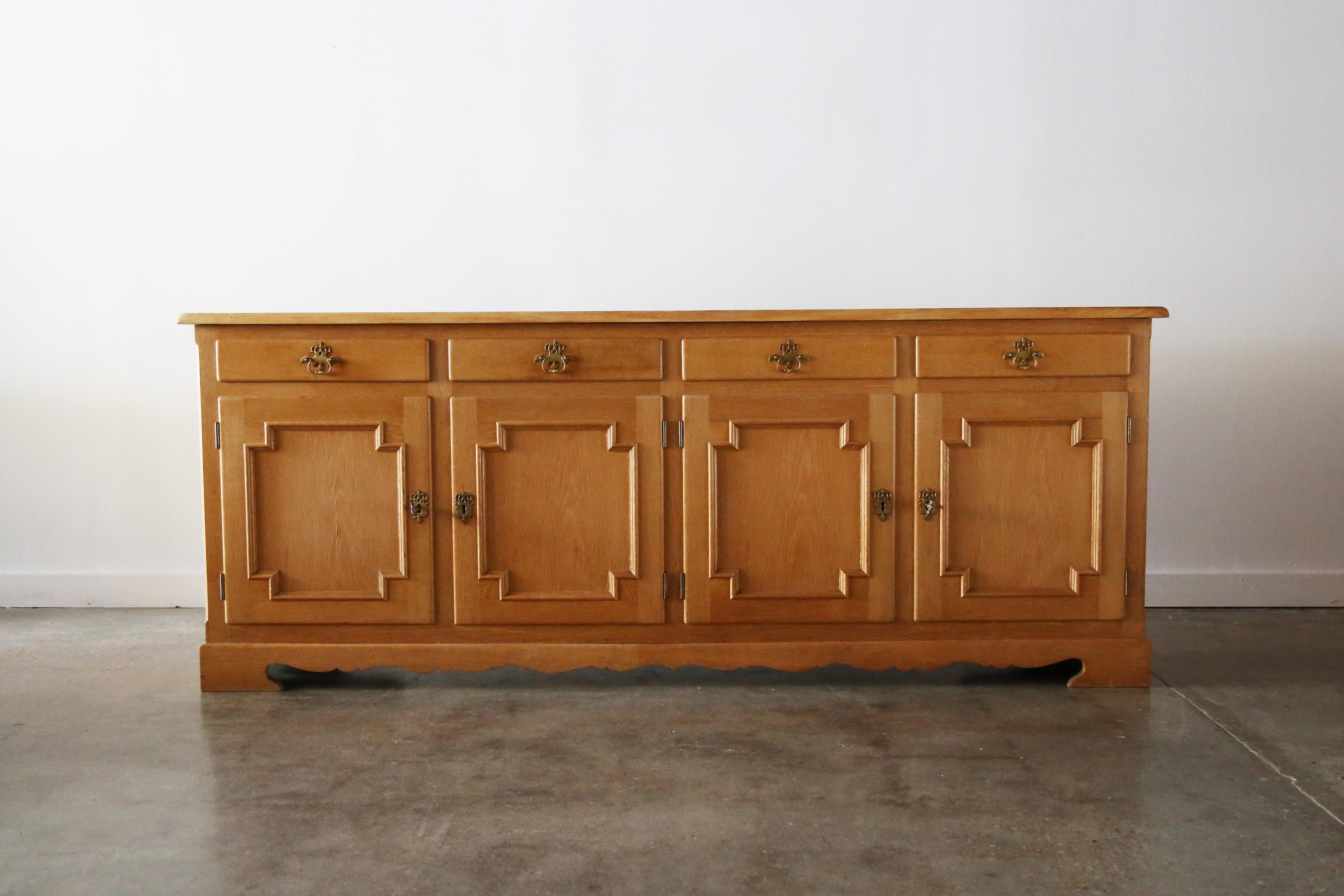 Beautiful quarter sawn solid white oak credenza / sideboard in the manner of Henning Kjaernulf. Danish mid-century oak sideboard in the style of Henning Kjærnulf. Features four doors with adjustable shelves. Each door secured by a locking mechanism