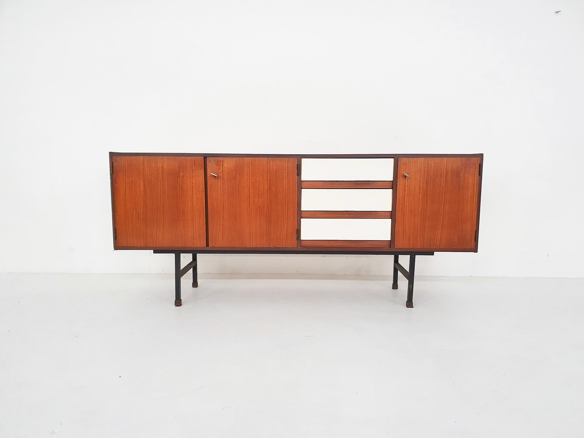 Teak veneer desk with 2 doors and three white Formica drawers.

On black metal legs with wooden feet

In good condition with some traces of use. Top has been sand and varnished.
