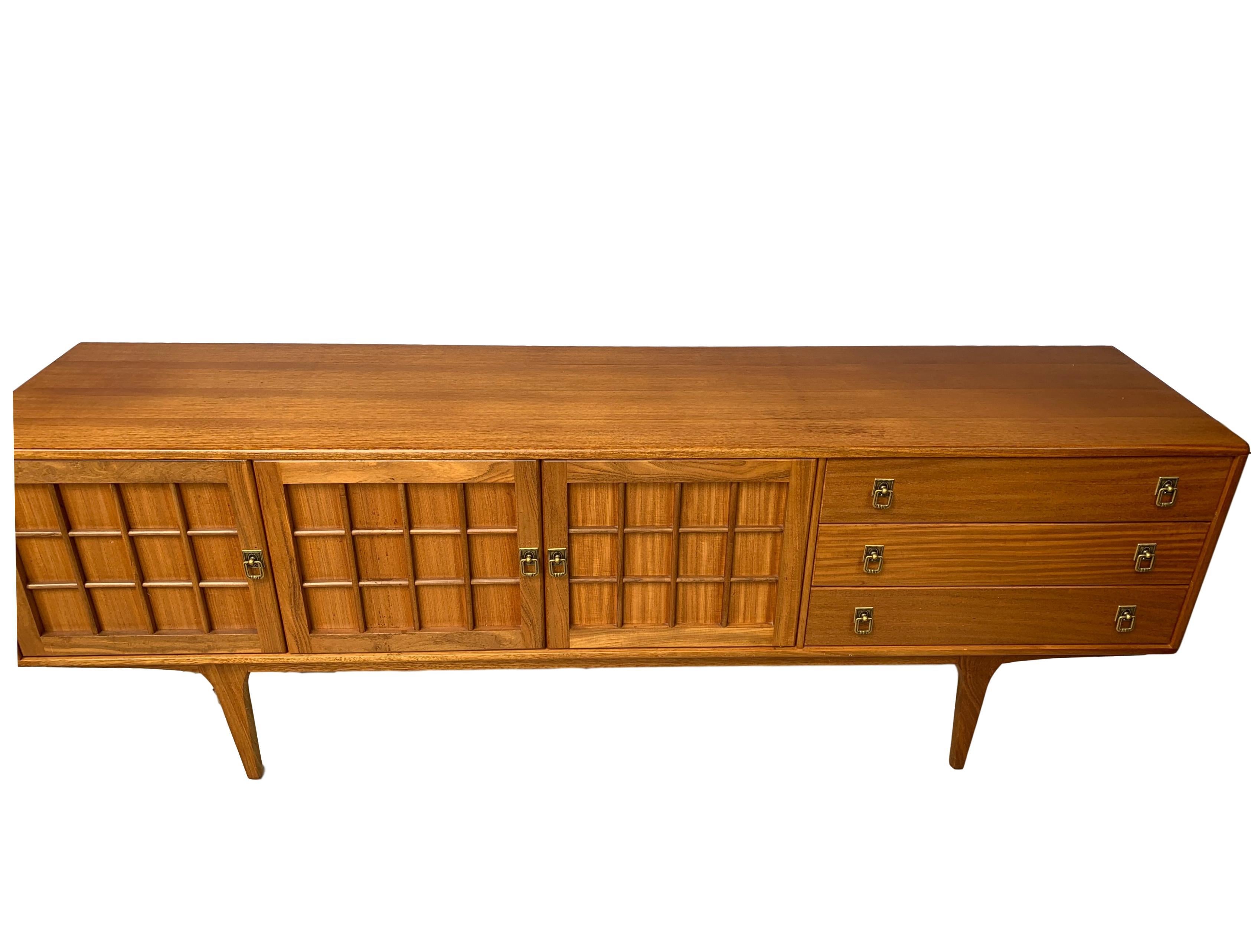 Mid-Century Modern sideboard credenza, teak, English, circa 1965, with molded raised panels, abundant storage space, and fitted silver drawer. Solid construction and built to the highest standard; you'll find no finer furniture