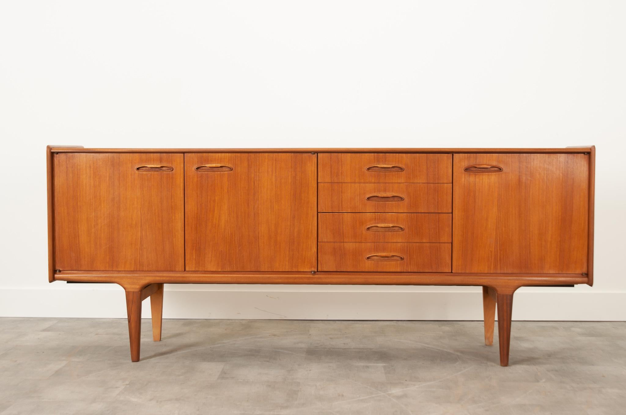 A sizable mid-century modern sideboard from France with a sleek, uncluttered design.  Vibrant mahogany with classic mid century modern elements make this a versatile piece. A bank of four drawers provide plenty of organized storage- the top drawer