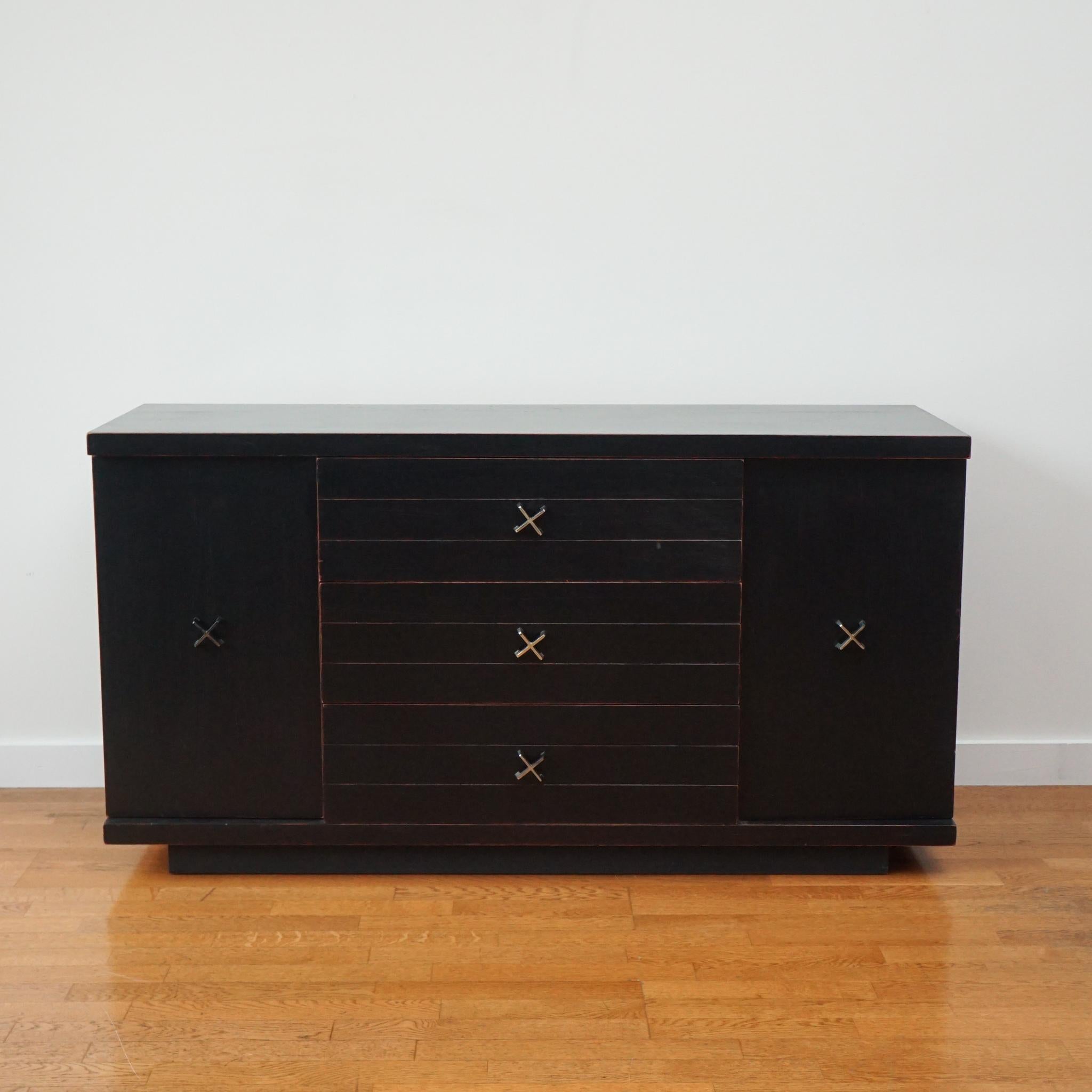 Handsome mid-century modern sideboard in a distressed matte black finish. 
Three center drawers and side cabinets with built-in shelves provide abundant storage.  The X-crossed nickel hardware is a nod to the work of Paul Frankl. 