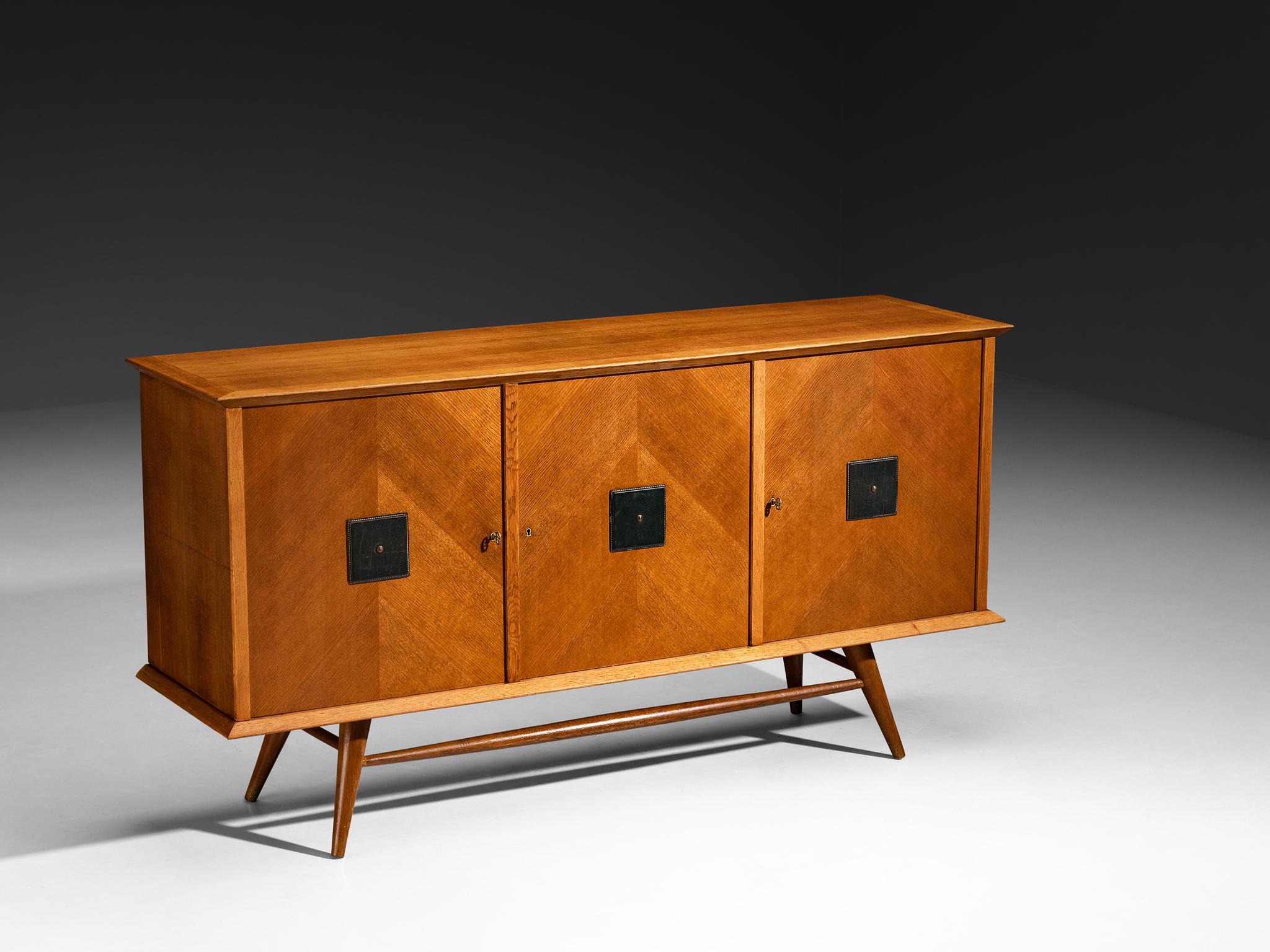 Credenza, Oak, pelle, ottone, Europa, anni '60

Credenza scultorea moderna di metà secolo con intricati dettagli geometrici. Il pezzo poggia su eleganti gambe affusolate che creano un senso di apertura e ne esaltano il fascino scultoreo, bilanciando