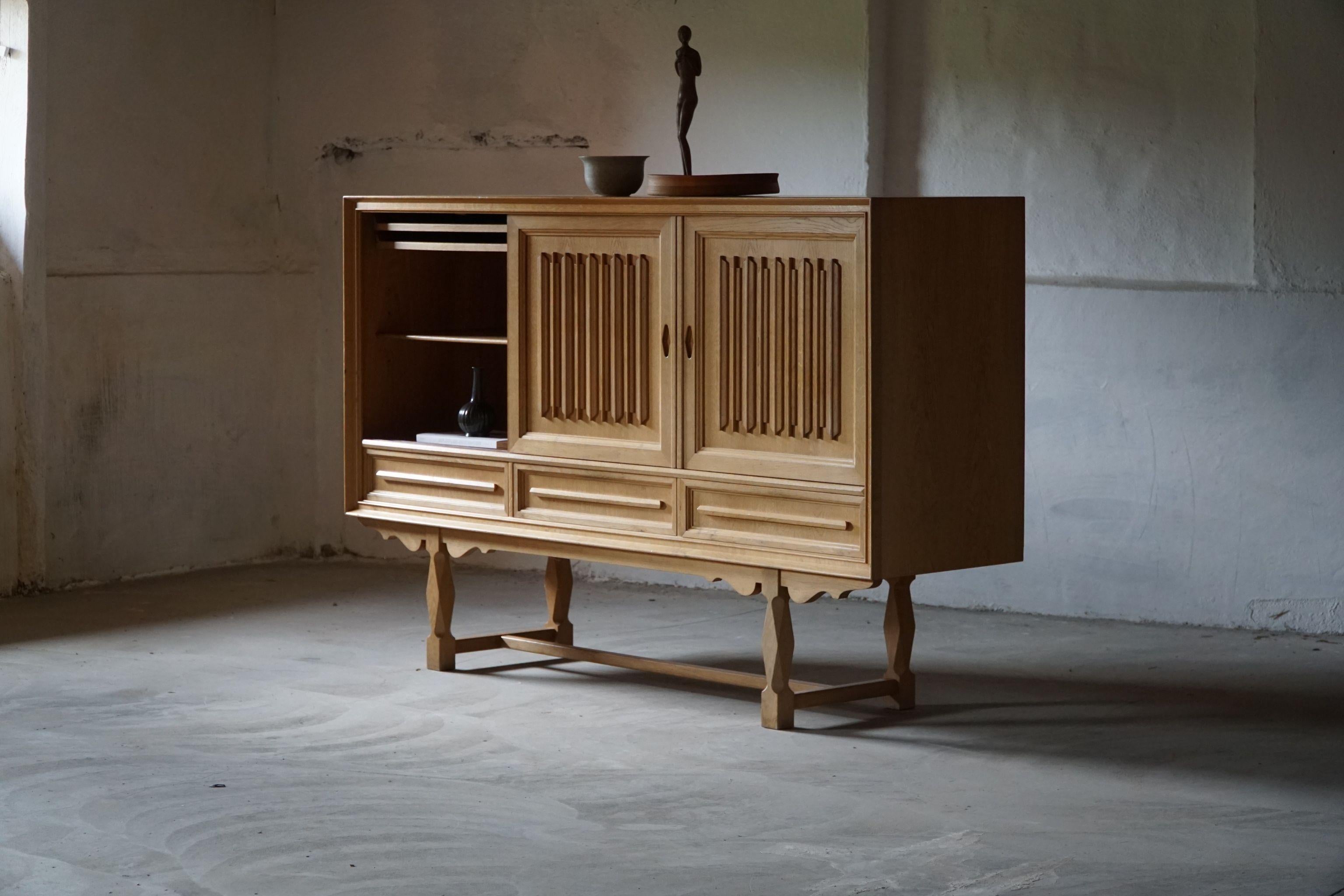 A sculptural high rectangular classic sideboard / cabinet in solid oak with plenty of storage and a nice carved front design. Made by a Danish cabinetmaker in ca 1960s. 
This piece is in a good vintage condition. Traces of wear.

A fine brutalist