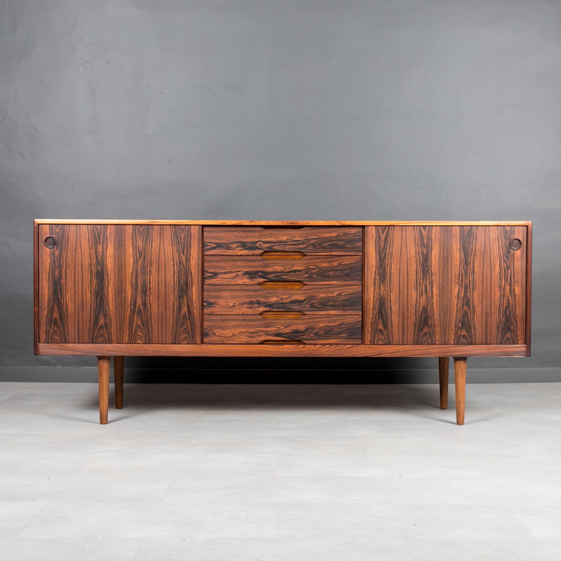 This sideboard was made in Norway around 1960s. The piece features three storage sections that reveal lots of storage space and are easily accessible with sliding doors. Both side sections are equipped with a single shelf. In the middle section you