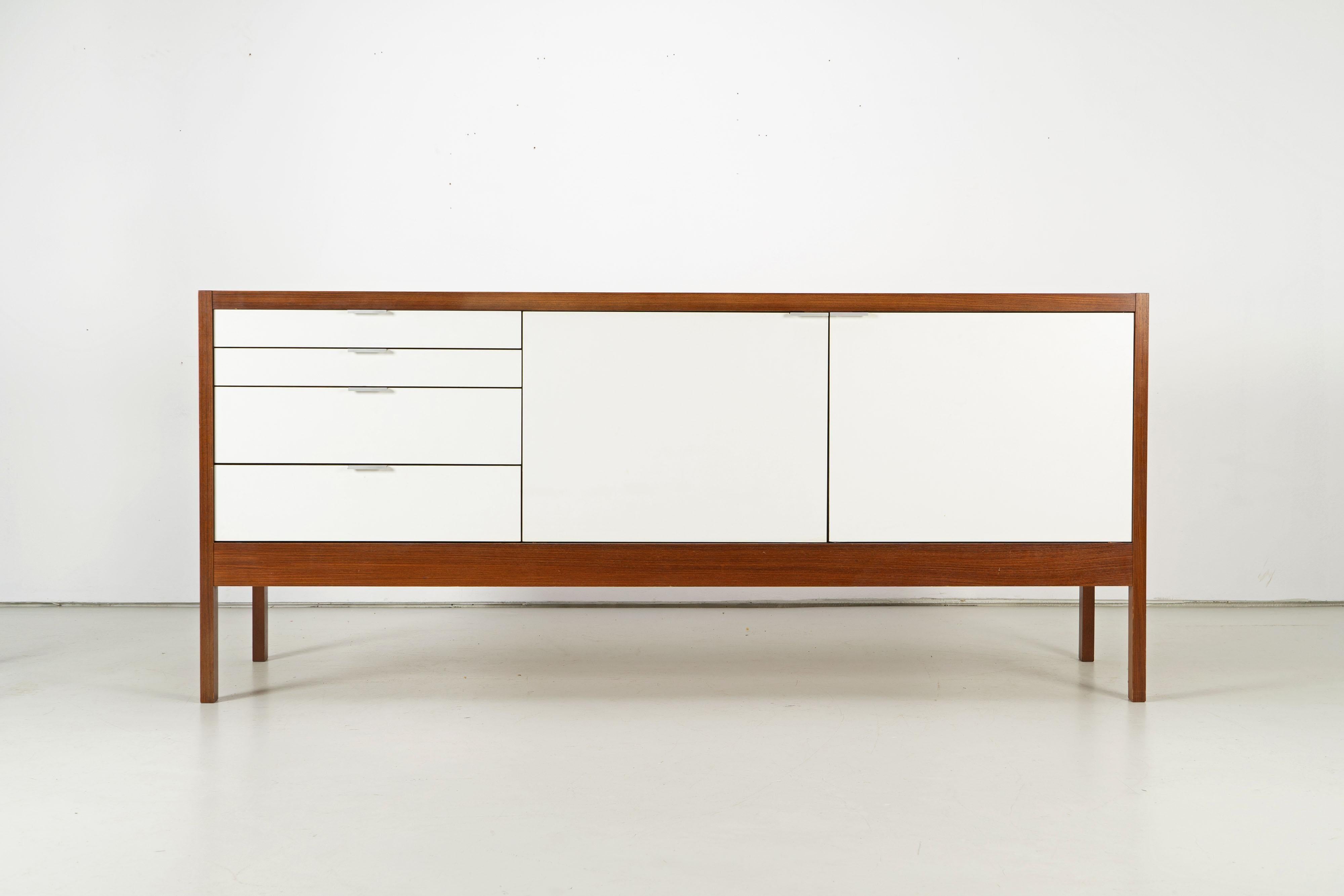Dieter Waeckerlin designed the Series 3 sideboard for Idealheim in 1963. Four drawers of different sizes and two doors form the front of the piece of furniture. Three slide-in shelves, that can be used at different heights, emerge behind the