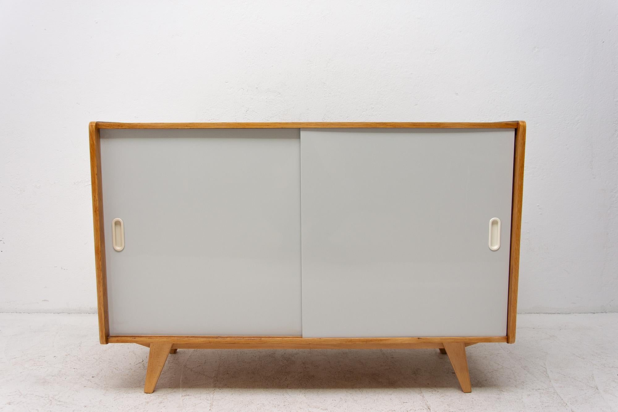 Midcentury sideboard, catalogue No. U-452, designed by Jiri Jiroutek. It features a sliding doors and one long shelf inside. It´s made from the beechwood, veneer, plywood and laminate. In excellent condition, fully refurbished.