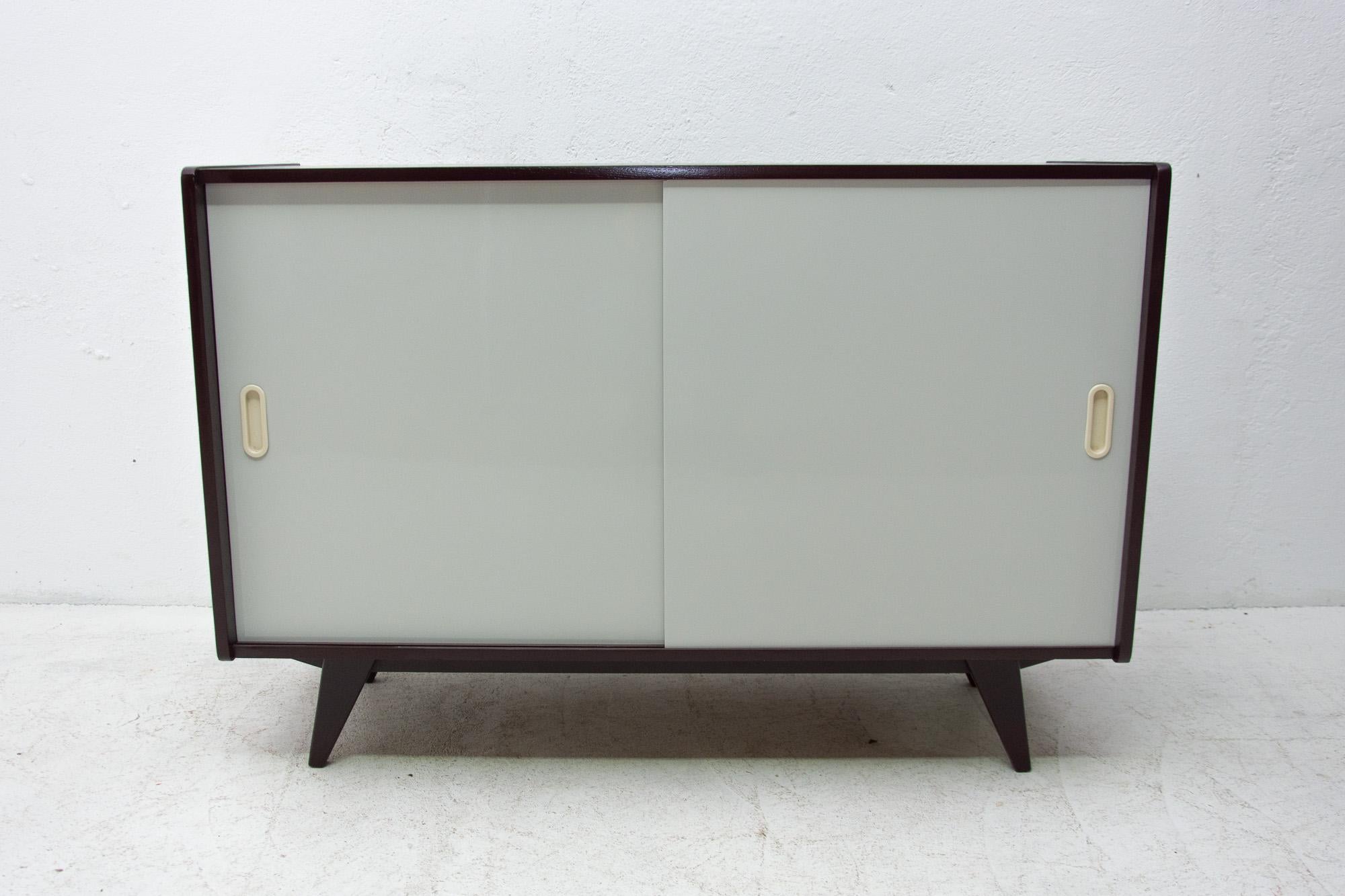 Midcentury sideboard, catalogue no. U-452, designed by Jiri Jiroutek. It features a sliding doors and one long shelf inside. It´s made from the beechwood, veneer, plywood and laminate. In excellent condition, fully refurbished. Dark stained surface,
