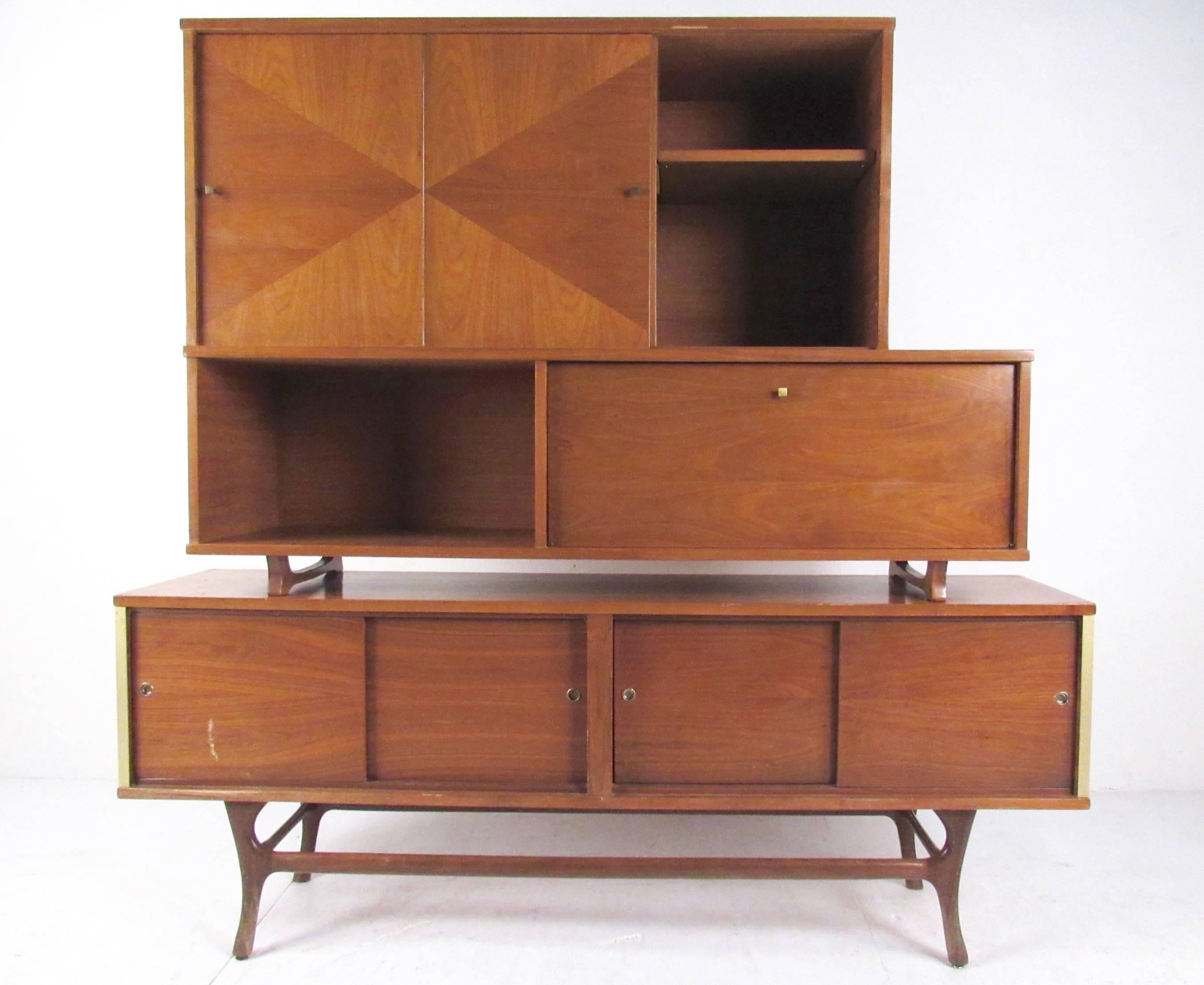 This stylish two-piece sideboard features a stylish mix of midcentury design details to make an impressive modern addition to home or office decor. Spacious shelved storage, sliding door access, and shapely hardwood legs add to the vintage appeal.