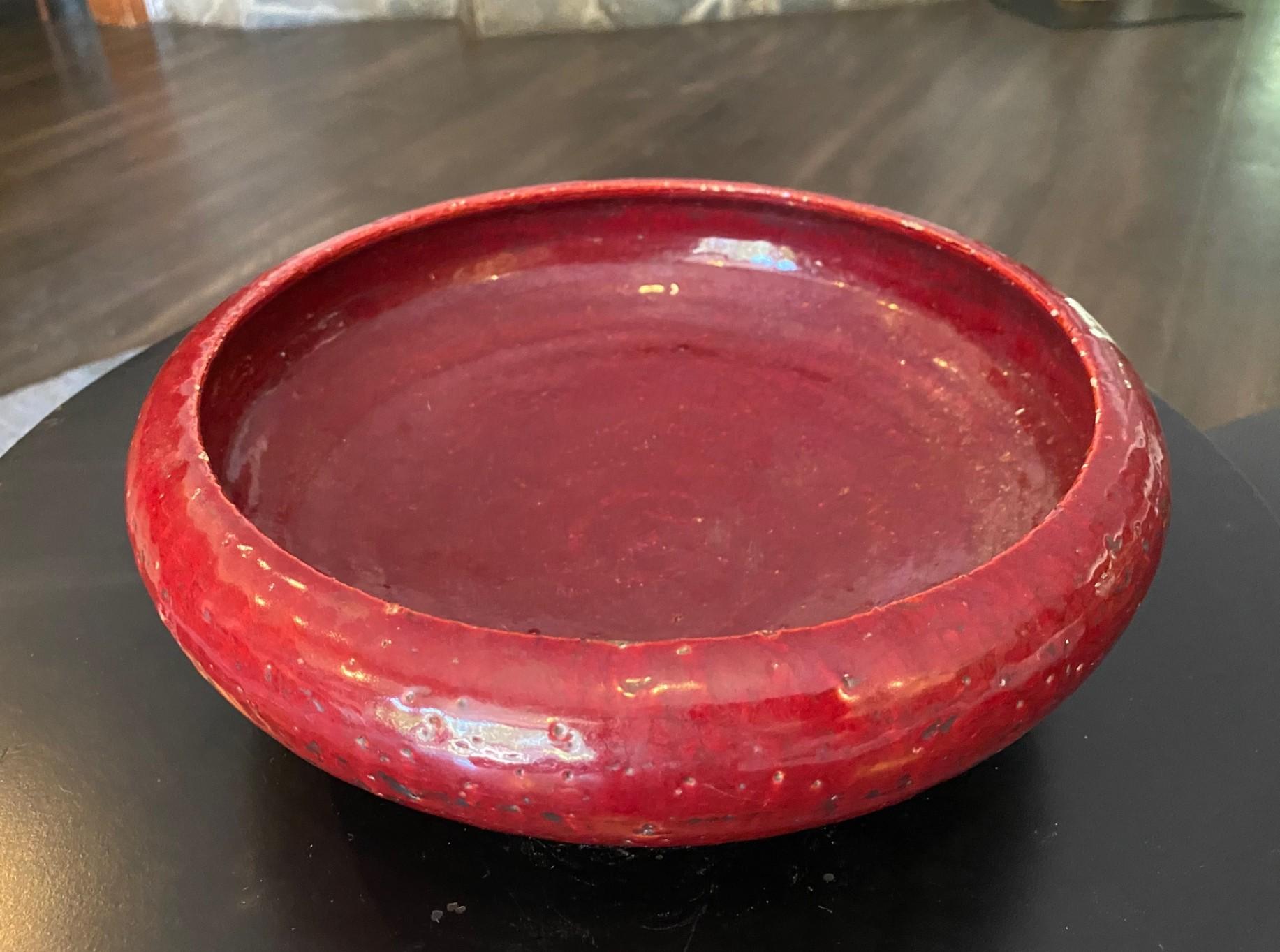 A beautiful, quite substantial and heavy, Italian pottery bowl featuring a sumptuous oxblood lava glaze that absolutely radiates in the light.  We believe this work is likely an Aldo Londi piece, perhaps for Bitossi.  It is exquisite in every way. 
