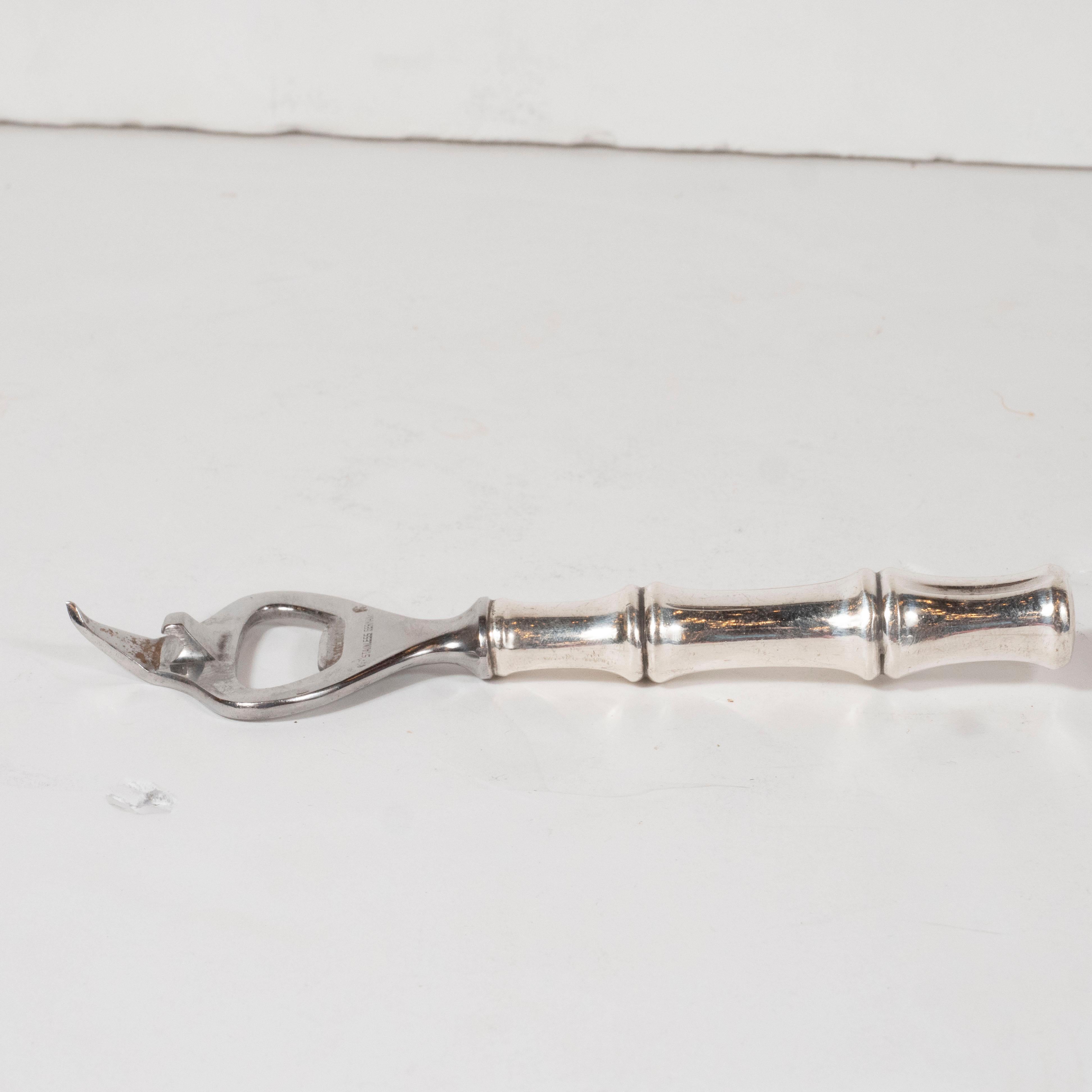 This elegant Mid-Century Modern bottle opener was realized by the fabled American design firm Tiffany & Co. in Germany circa 1950. It features a stylized sterling silver bamboo handle that flares into an ovoid head with a open center and a pointed