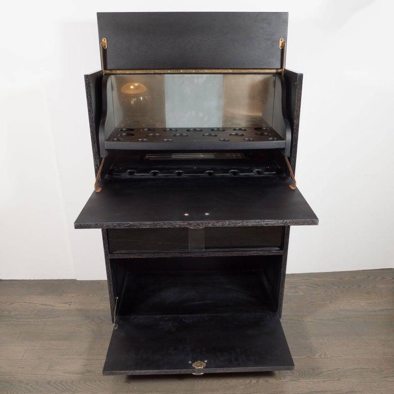 This sophisticated Mid-Century Modern dry bar was handcrafted in silver cerused oak in the United States, circa 1950. The top compartment offers three rows of circular depressions, in differing diameters, perfect for storing a variety of glass ware