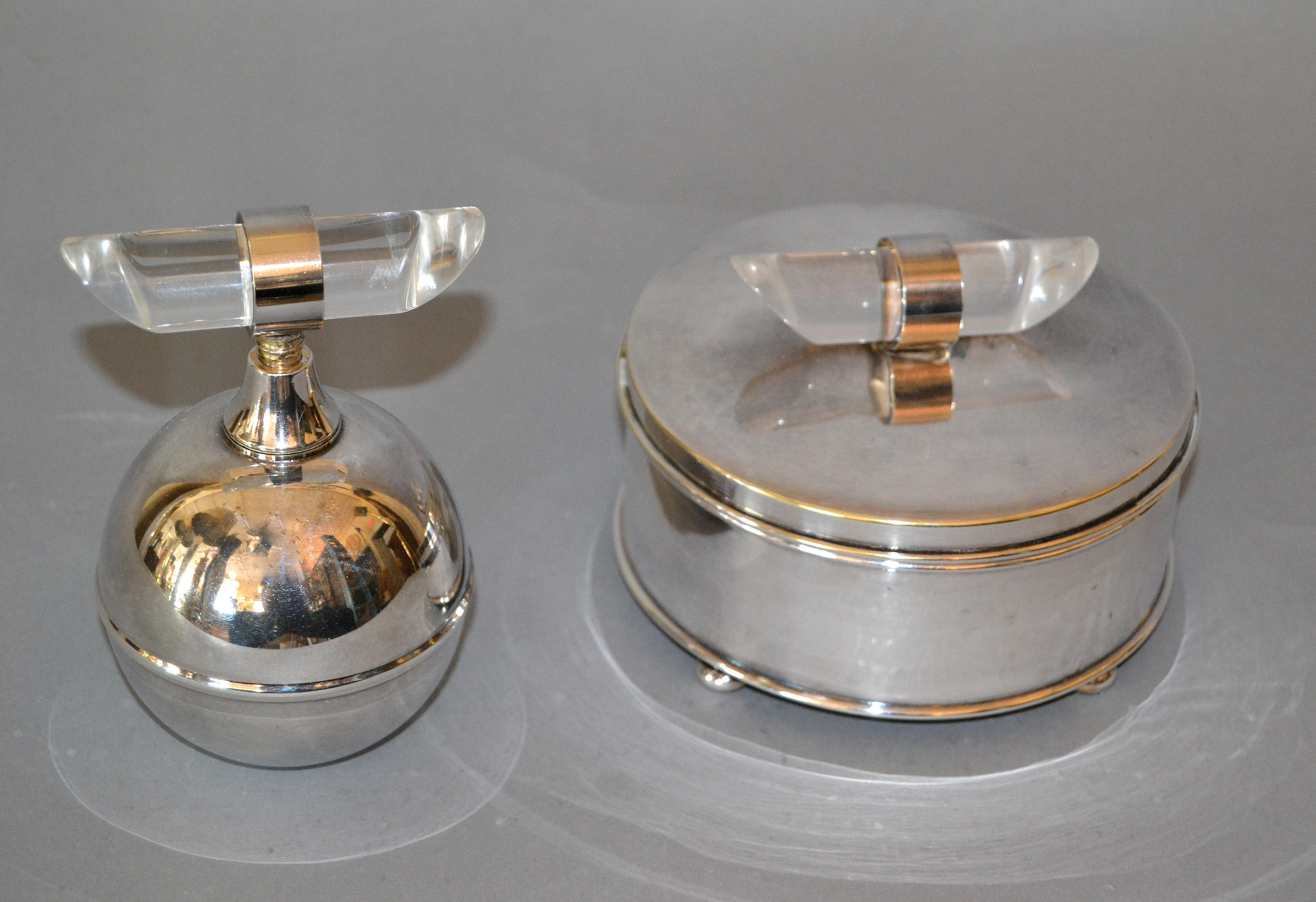 Elegante juego de tocador Moderno de Mediados de Siglo compuesto por un frasco de perfume bañado en plata y un cuenco de cristal con polvera bañada en plata.
El pomo artesanal de Lucite decora las dos piezas.
Marcado debajo Apolo y Apolo A