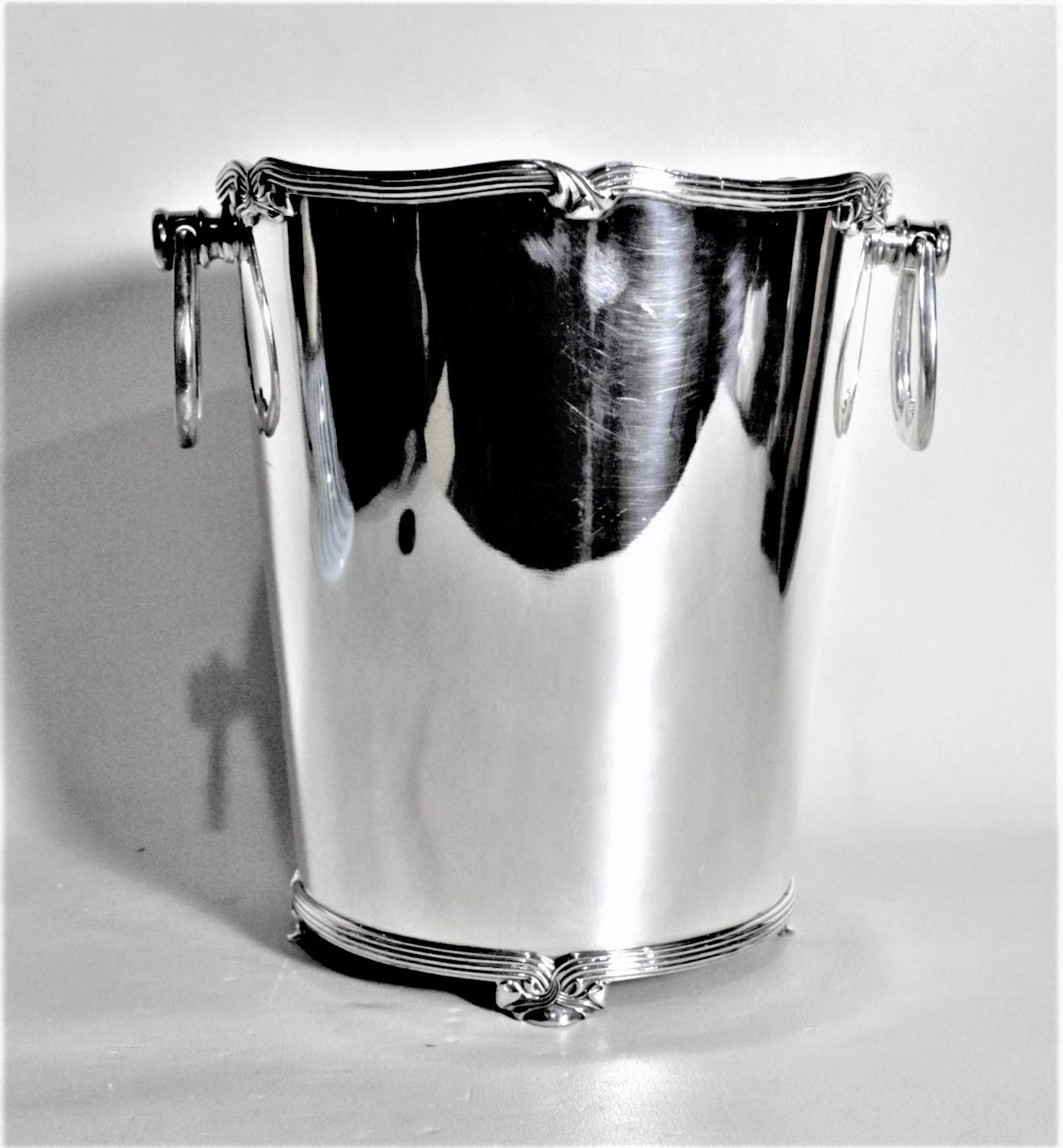 This sturdy and well made silver plated ice bucket is presumed to have been made in Italy in approximately 1965 in a Hollywood Regency style. This footed ice bucket has two ribbed and scrolled handles that hang on sturdy posts. The bucket is