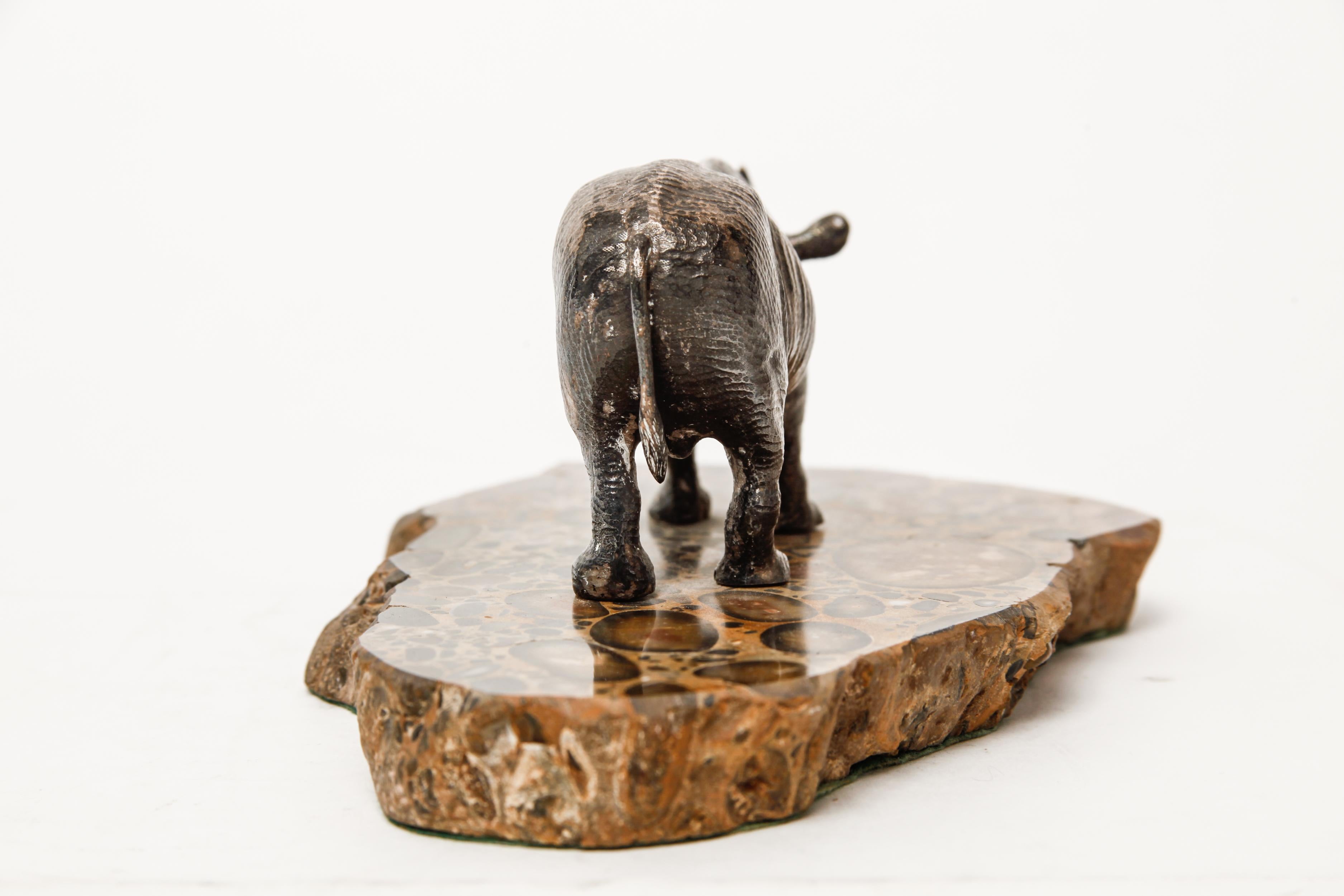 Mid-Century Modern silver plated sculpture of a rhinoceros standing atop a base made of pudding-stone marble. The piece is in great vintage condition with age-related wear and some loss to the silver plating.