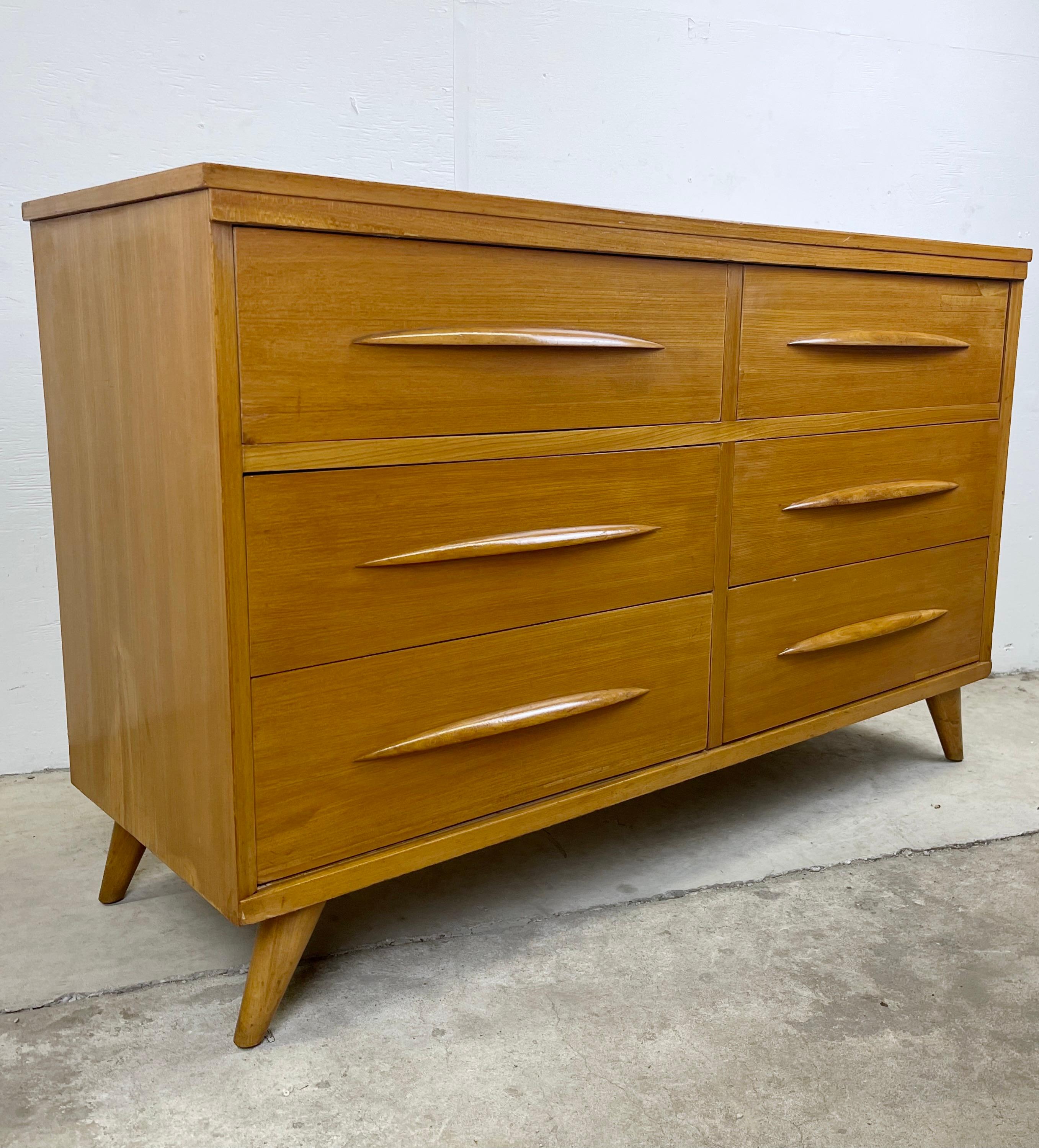 This impressive Mid-Century Modern six drawer dresser features a beautiful vintage blonde finish with unique pointed wooden drawer pulls. The quality vintage construction and mid-century modern design of this six drawer bedroom dresser make it the