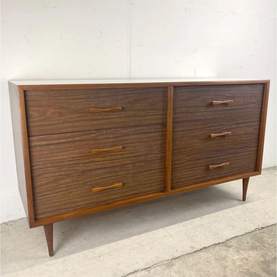 This stylish Mid-Century Modern dresser offers six spacious drawers for plenty of bedroom storage in a petite package. The bowtie handles and faux walnut finish add a warm modern centerpiece to any room while complimented by the durable white