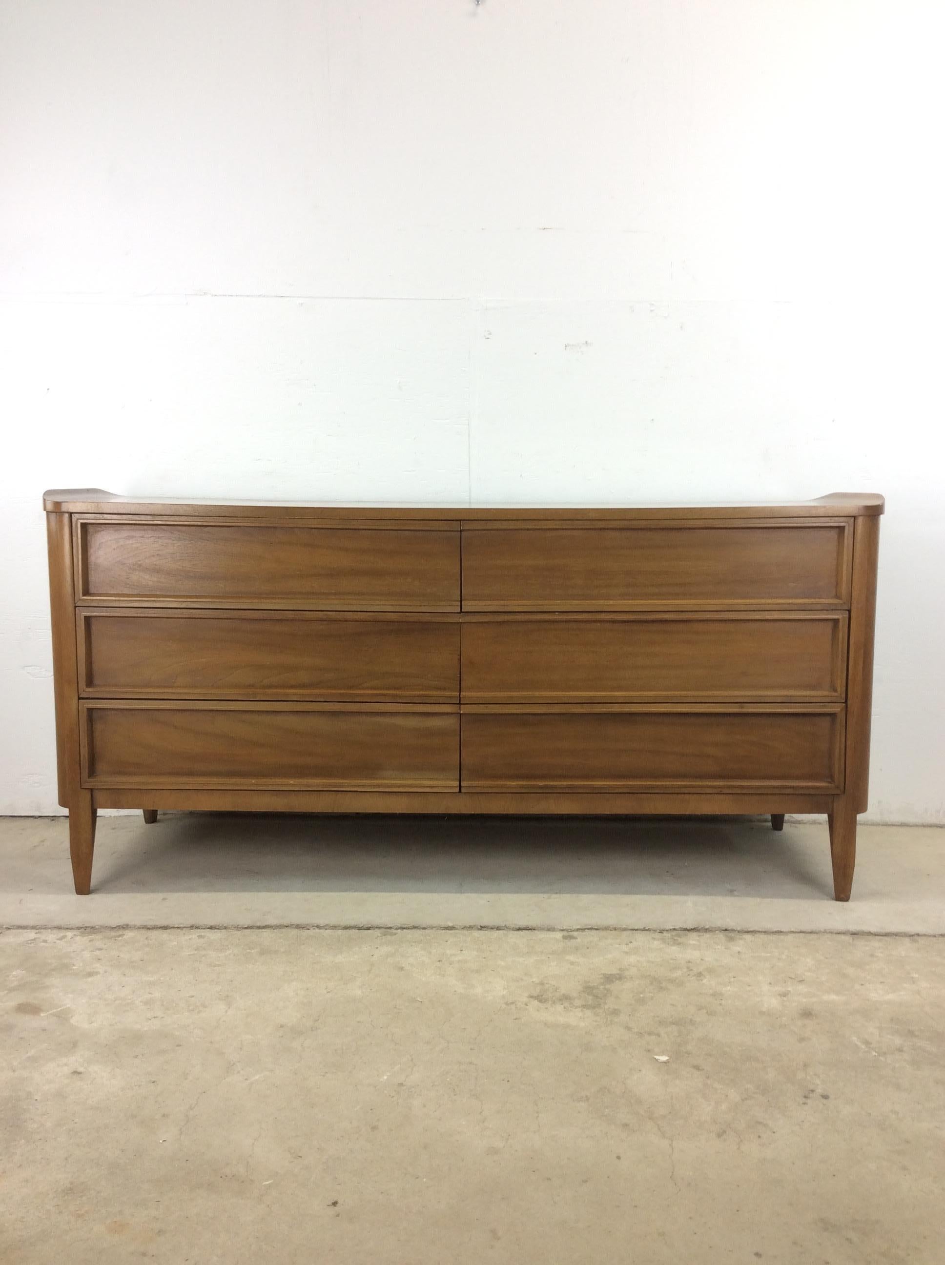 Esta cómoda baja moderna de mediados de siglo de American of Martinsville tiene estructura de madera noble, acabado original en nogal, seis cajones con cola de milano, bordes curvados únicos en la parte superior y patas cónicas altas.

Dimensiones: