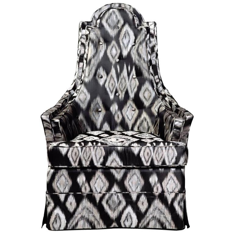 Silla de respaldo alto con faldón de los años 60 tapizada en tela Ikat negra y plateada. Esta silla escultural tiene un respaldo alto en forma de escudo con un perfil precioso. Presenta detalles de botones en la espalda, detalles de costura y base