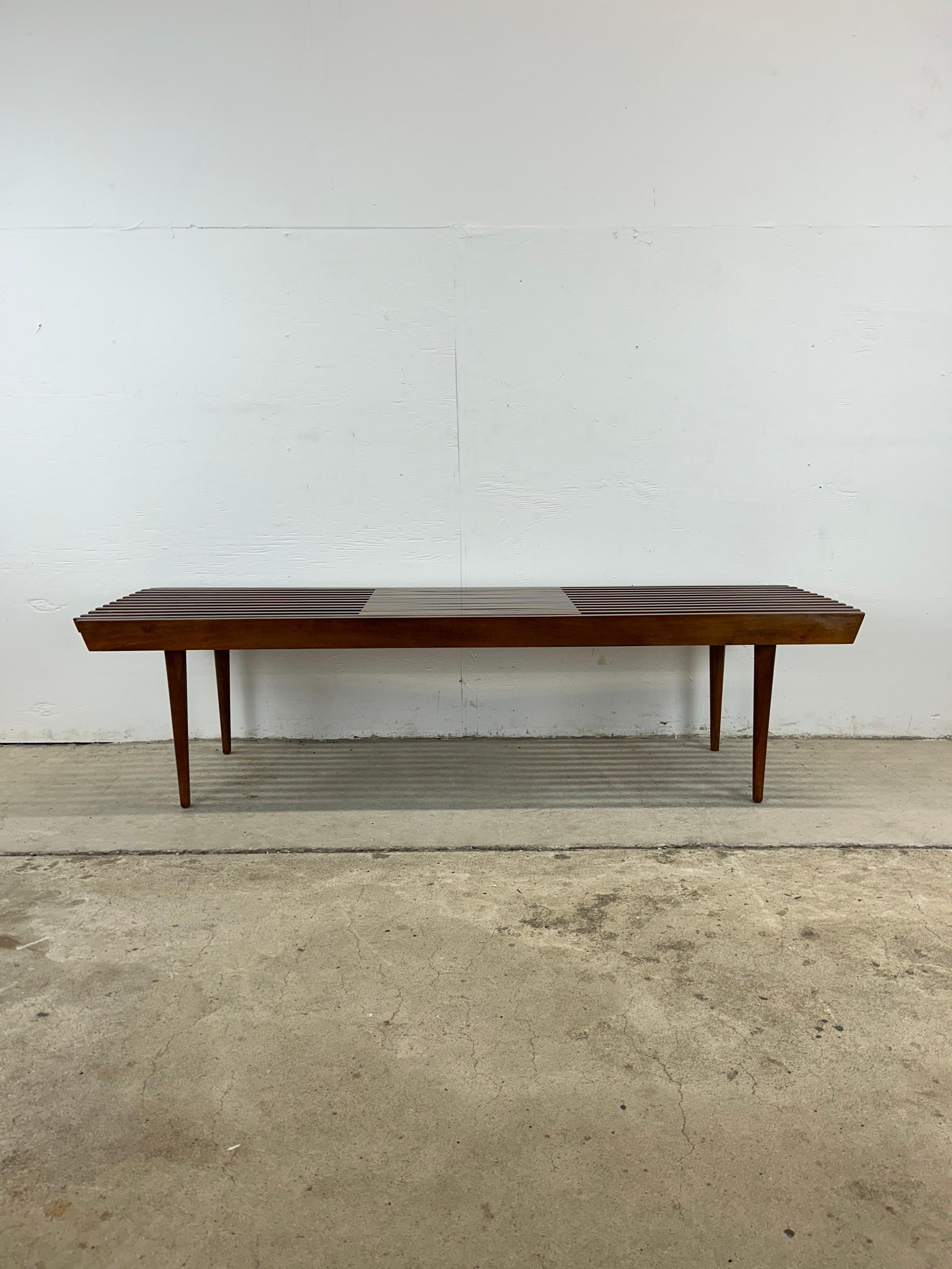 Ce banc à lattes moderne du milieu du siècle est construit en bois dur, avec une finition en noyer d'origine, un plateau réglable en largeur et en longueur et de grands pieds coniques.u2028u2028S'étend jusqu'à environ 66