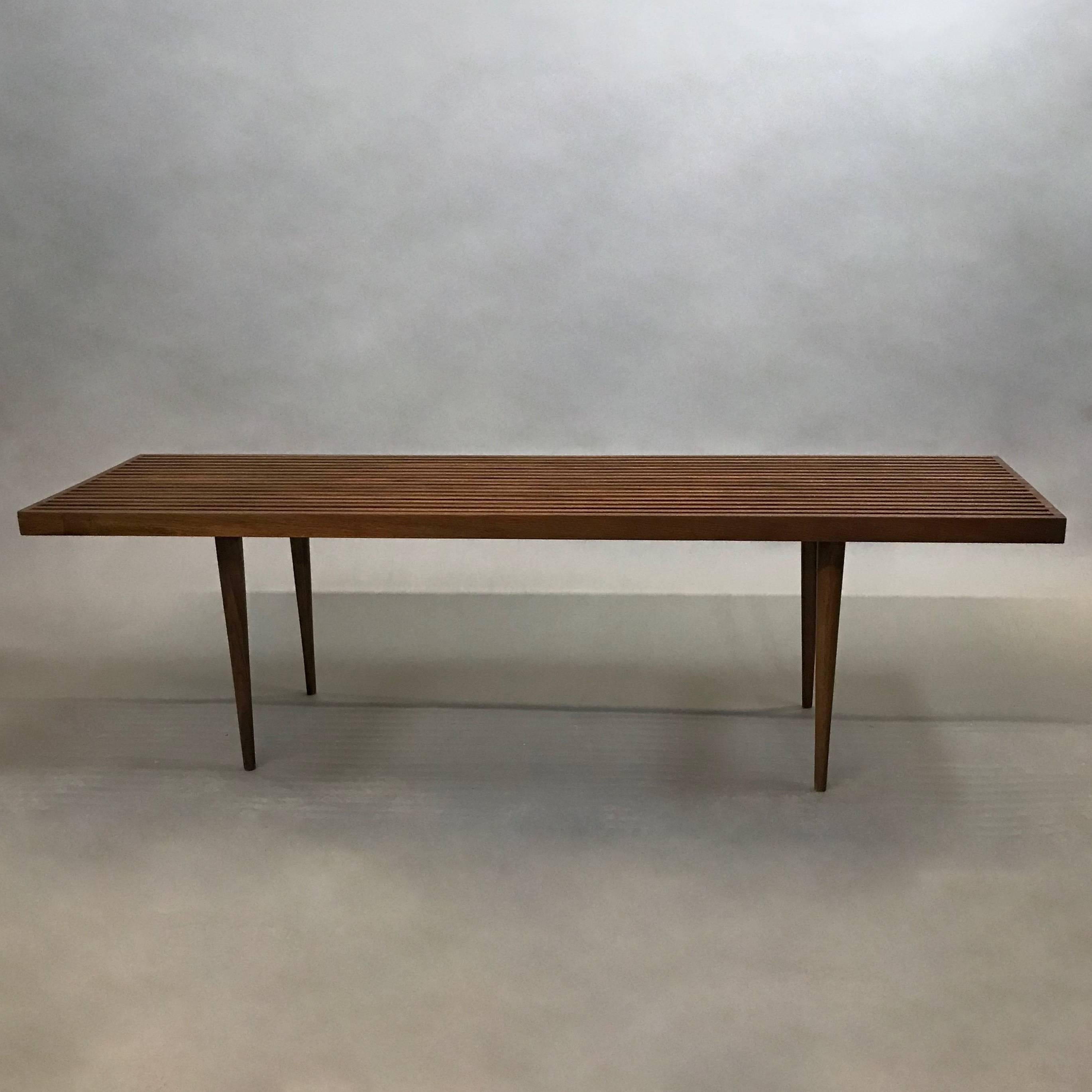 Mid-Century Modern, slatted walnut bench or coffee table with elegant dovetail details and tapered legs designed by Mel Smilow.