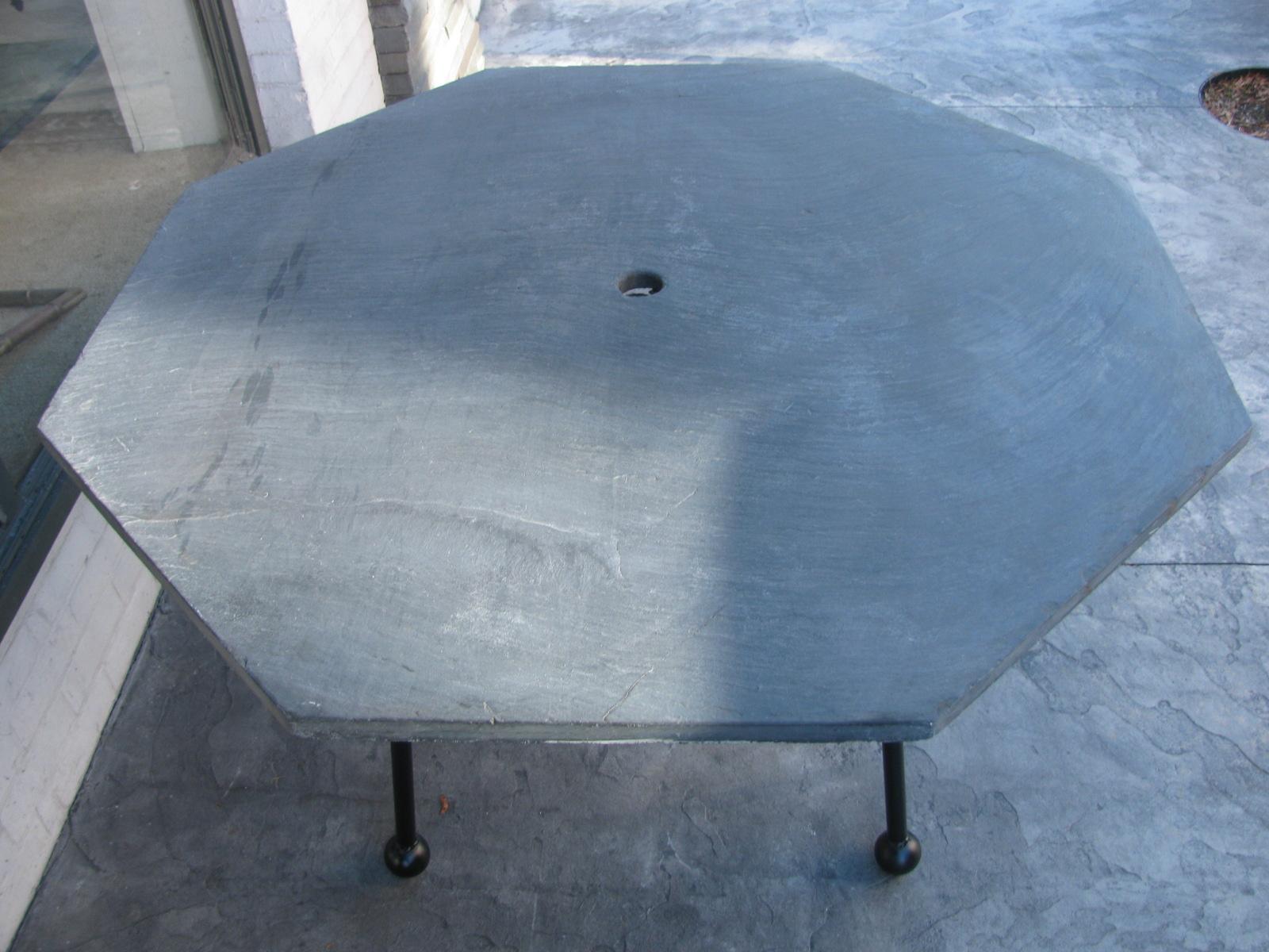 Fabulous octagonal slate top table by the Russell Woodard Co. Almost 1 inch thick with an umbrella hole cutout in the center. Wrought iron base with ball feet for support, was just recently painted black. Perfect for the patio outdoor area. All in