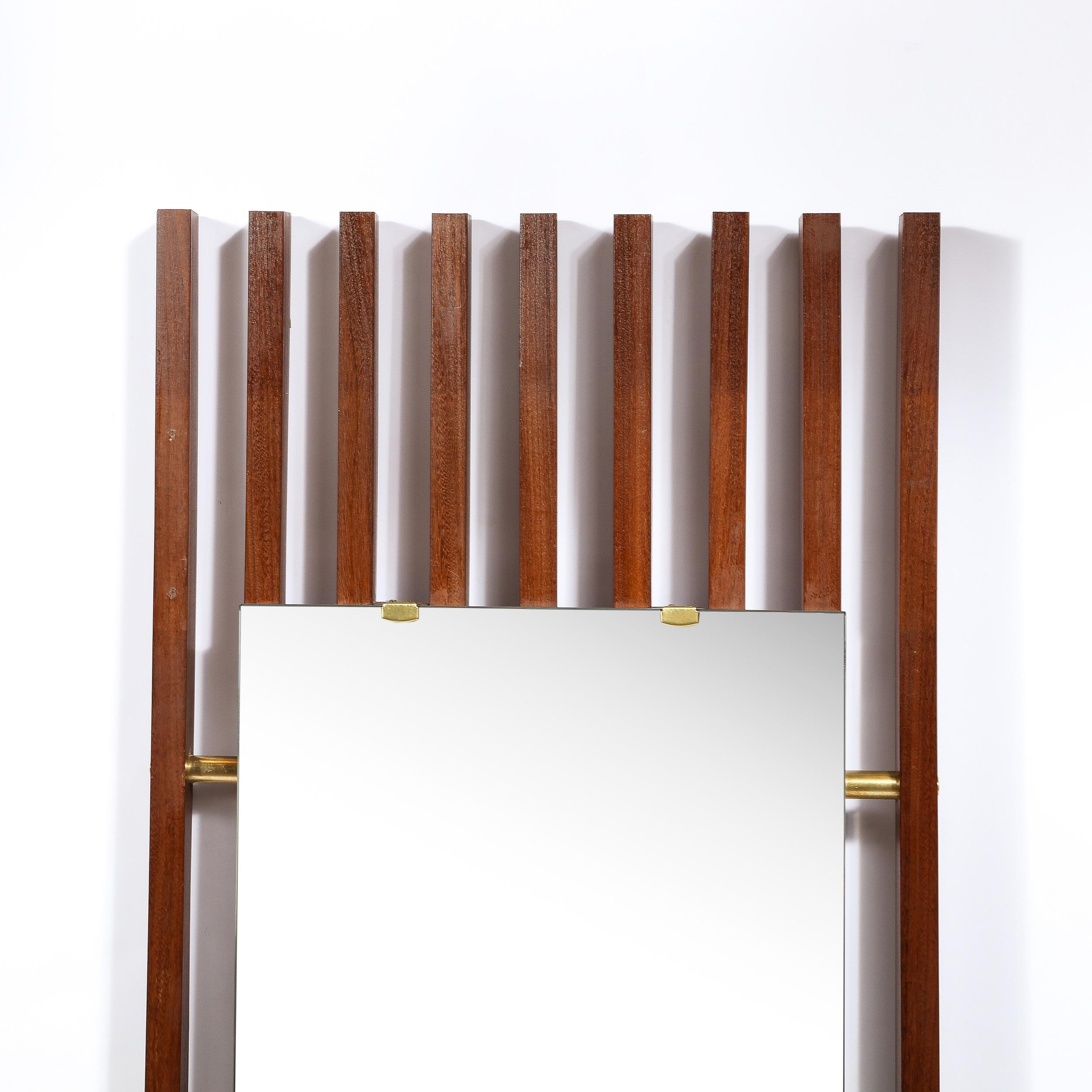This beautiful Mid-Century Modern mirror was realized in France circa 1960. It features rectangular mirrored panels secured to slatted bodies of rectangular walnut via brushed brass supports. Brass cylindrical supports piece through the walnut frame