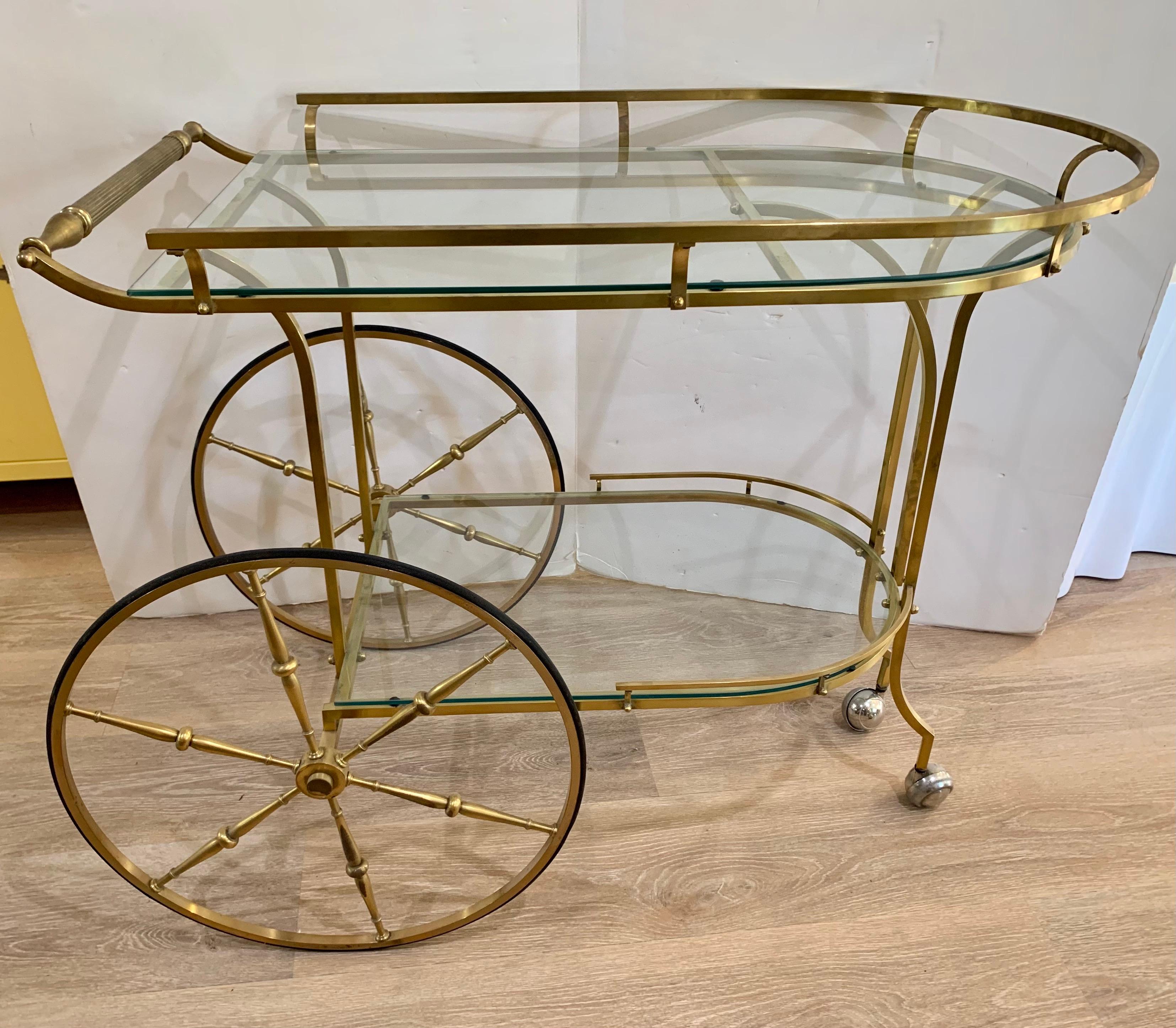 Iconic two-tier mid-century modern brass and glass bar cart with coveted large rear wheels and railing at top tier. Spectacular in every way! Now, more than ever, home is where the heart is.