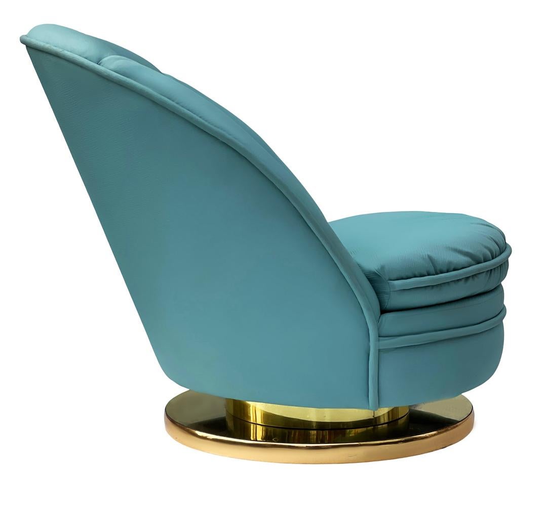 A swiveling and tilting slipper chair by Milo Baughman circa 1980s. It features the original blue fabric with a brass base. Fabric is original and could be further used.