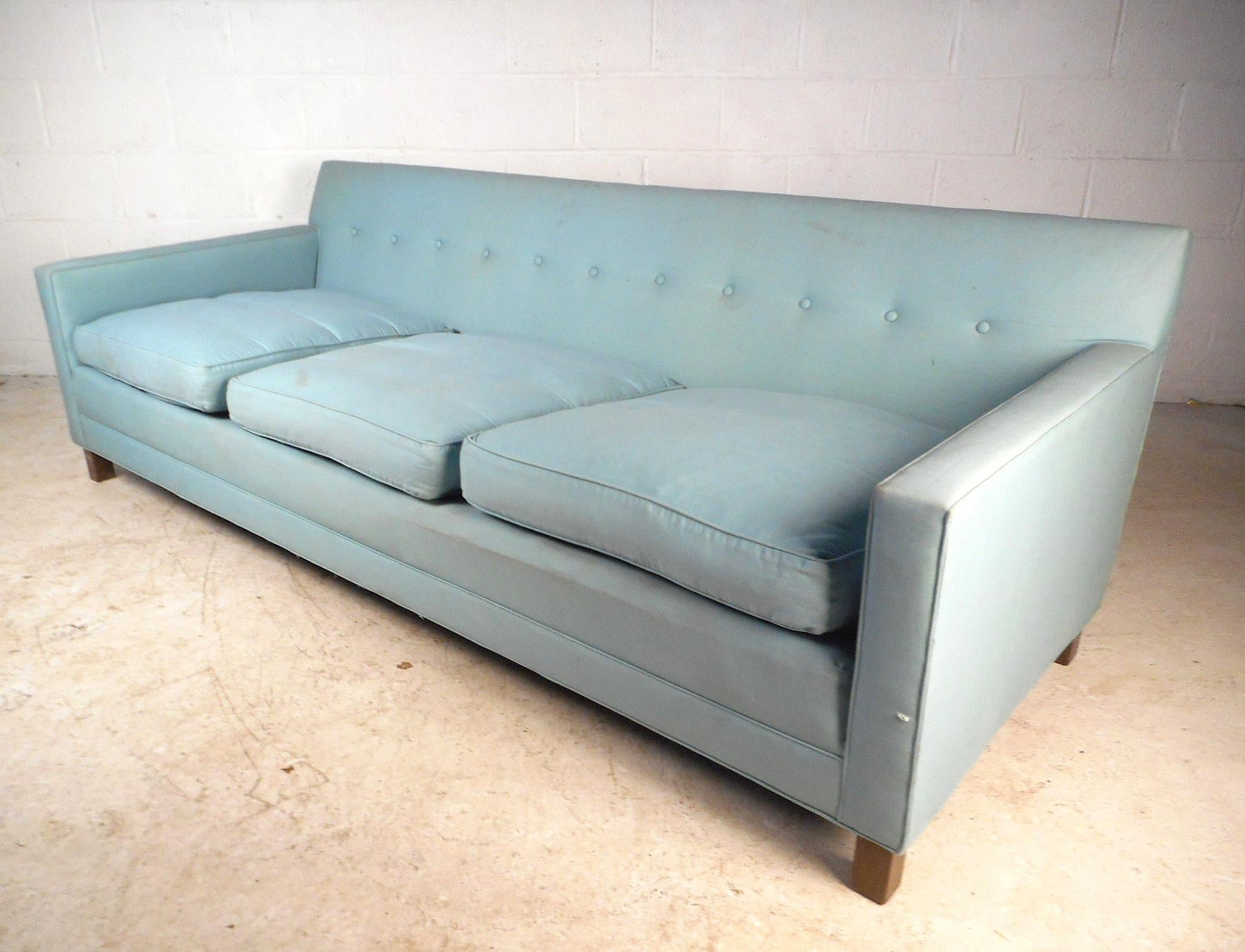 This Mid-Century Modern sofa by Dunbar features a uniformly tufted back and loose cushions. Sturdy walnut legs ensure stability while complimenting the sky blue upholstery. This sofa makes the perfect addition to any seating arrangement, circa 1960.