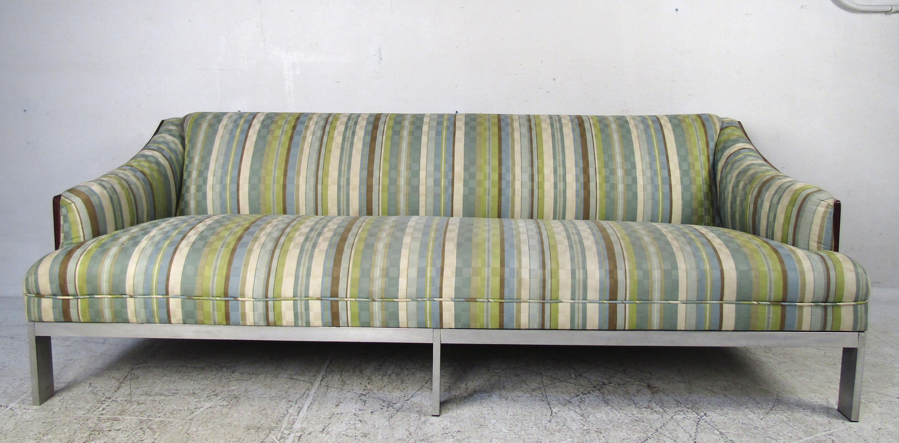 This stunning vintage modern sofa boasts a rich rosewood back and sculpted sides. Six flat bar chrome legs and overstuffed seating show quality construction and ensure maximum comfort. A colorful vintage fabric adds to the midcentury appeal. This