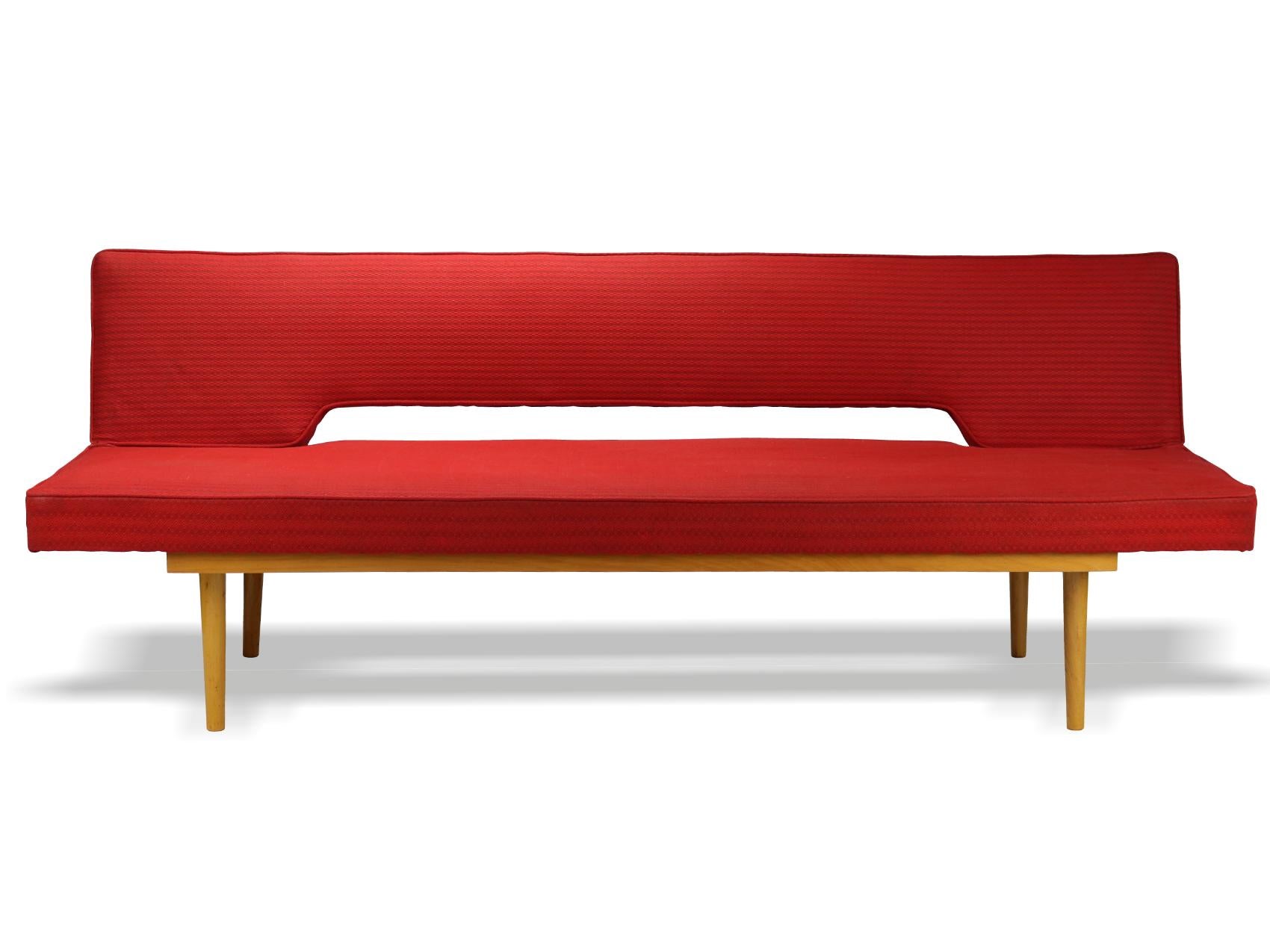 This sofa was designed by Miroslav Navratil in the 1960s fo Interier Praha Czechoslovakia. It features a beech frame with the original red fabric. It is easily folded out into a 90 cm wide bed,.