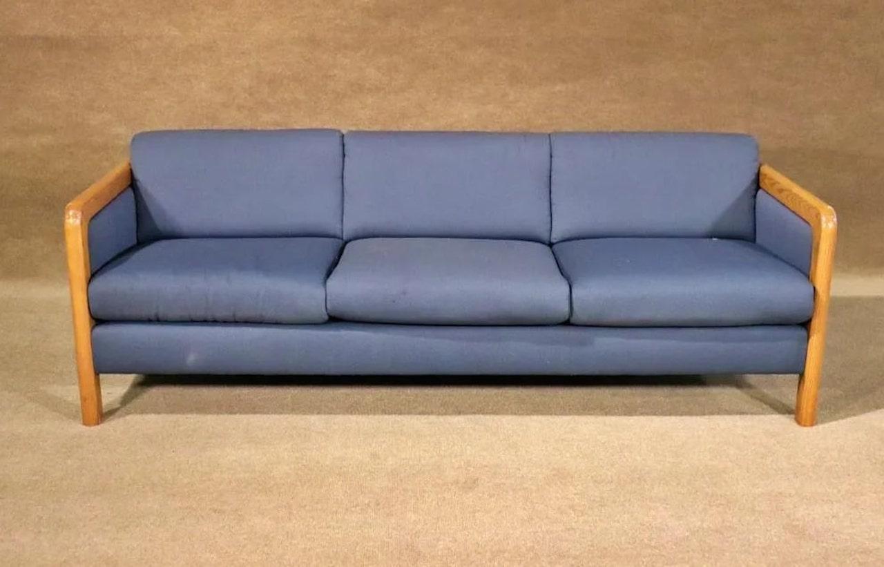 This attractive vintage modern sofa boasts a single overstuffed cushion covered in a plush royal blue upholstery. The unique drum shaped legs add to the allure. A straight line midcentury design with fabric that ensures plenty of comfort without