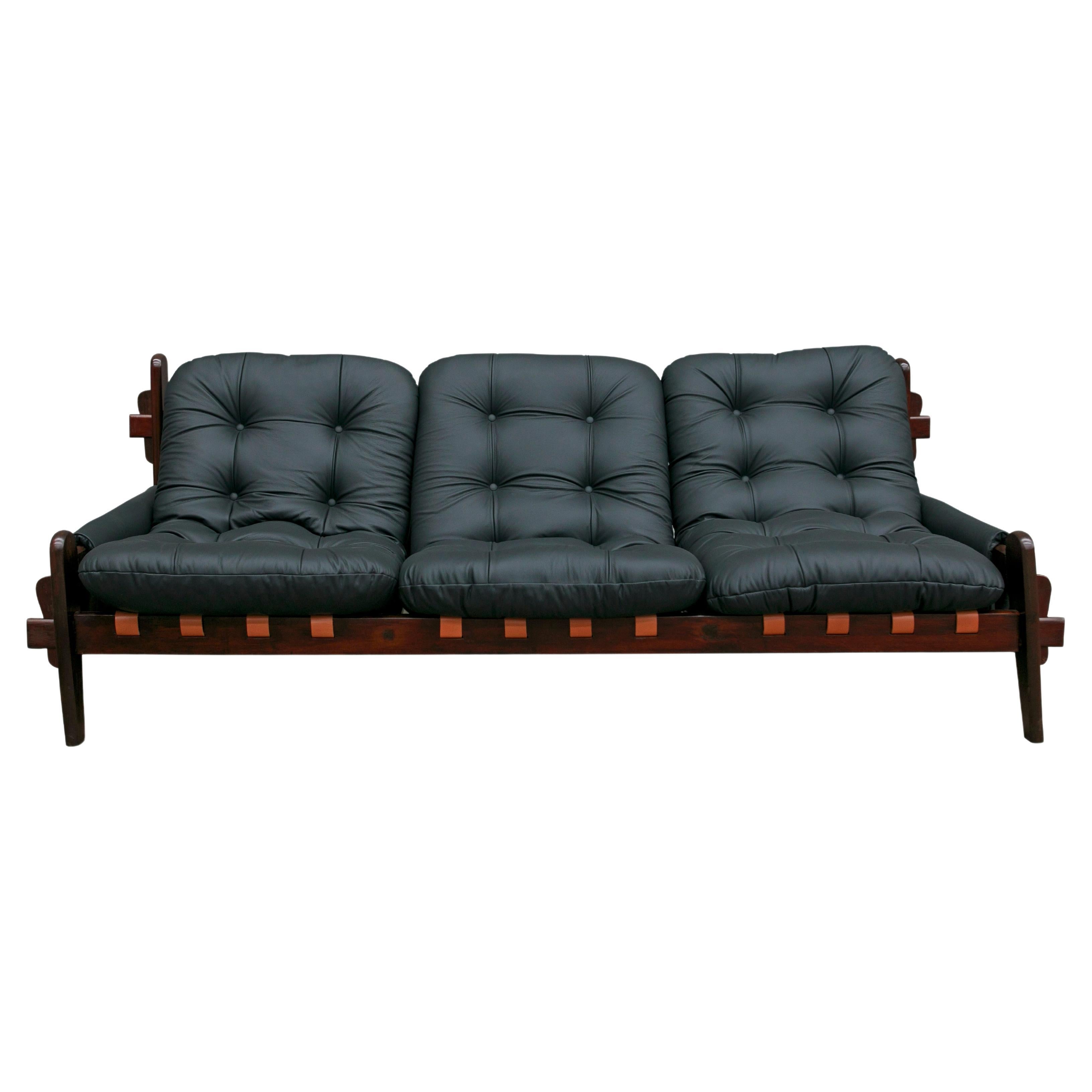 Available now, this very Brazilian modern sofa in black leather and hardwood designed by Jean Gillon in the seventies is simply spectacular!

This gorgeous, one-of-a-kind three seat sofa features a solid Brazilian Rosewood (known as Jacaranda)