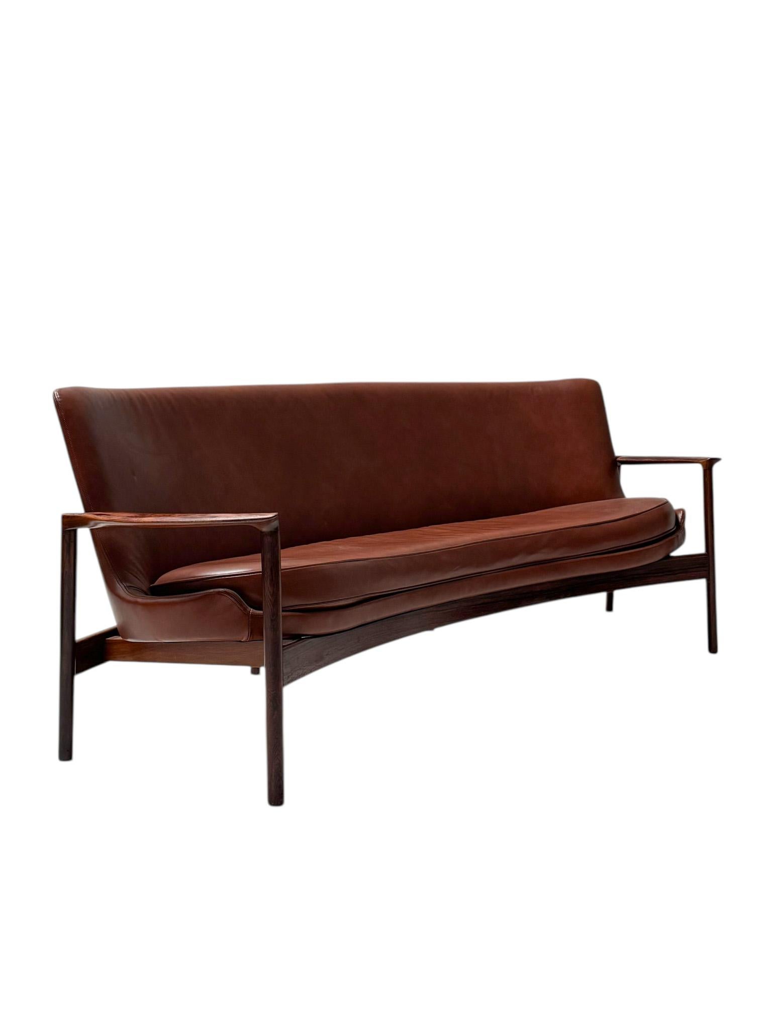Magnificent and rare Mid-Century Modern sofa or bench.
Design by Ib Kofod-Larsen for Frõscher KG Germany.
Striking Danish design from the 1970s.
Solid rosewood and original rosewood veneer frame with reupholstered seat in premium cognac