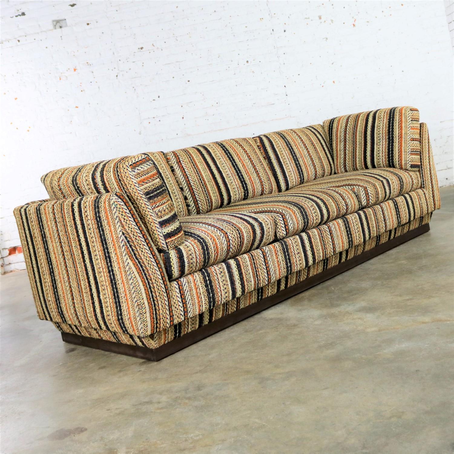 Lee Harvey original by Maddox Mid-Century Modern platform tuxedo sofa in its original striped fabric. This sofa is in fabulous vintage condition. Including the fabric. Apart from a small hole in the inside back which is hidden by the seat cushion.