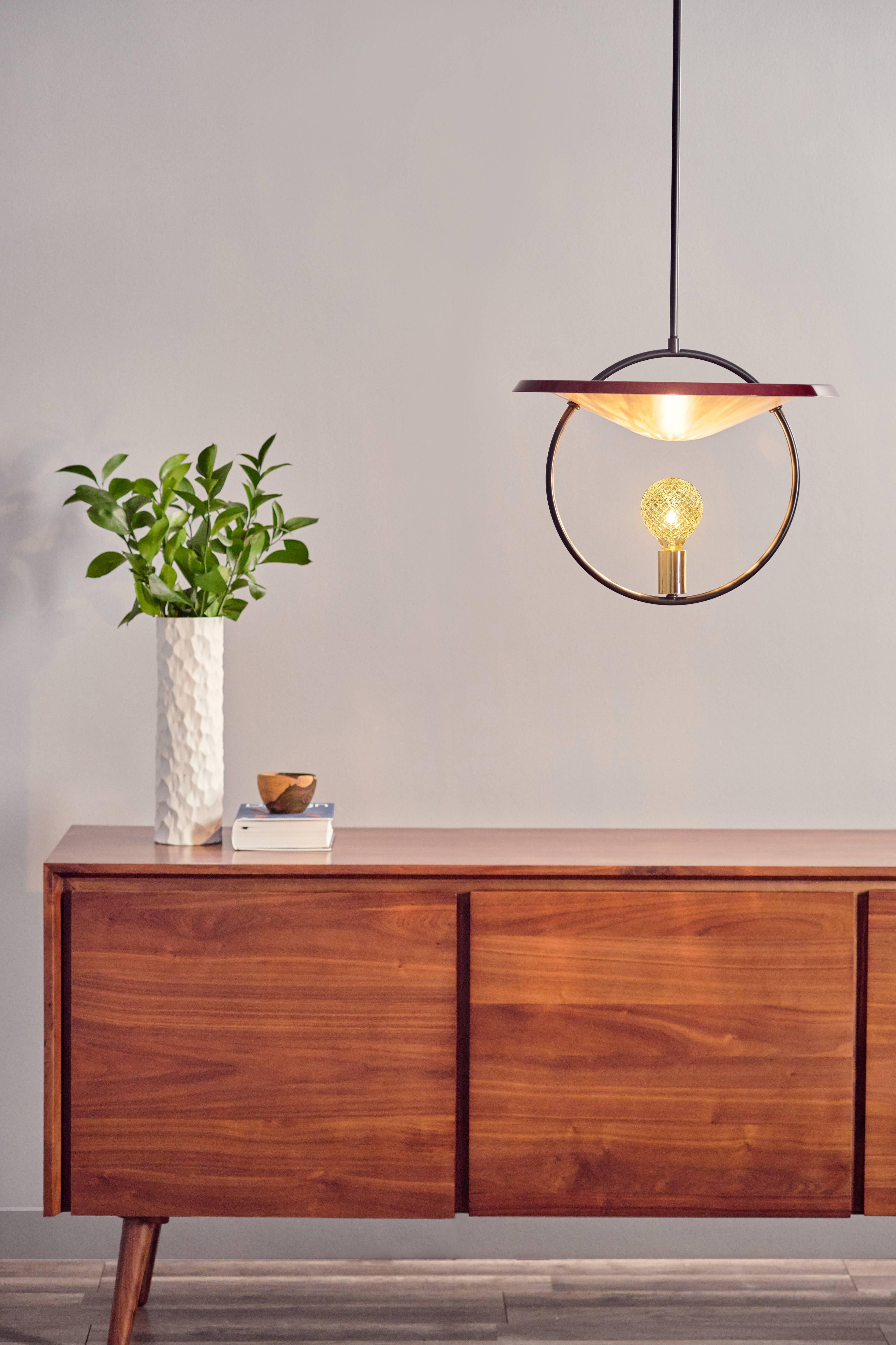 Create a weightless light sculpture with this Mid-Century Modern inspired pendant. A textured LED bulb casts stunning shadows and balances effortlessly inside of a sleek solid brass ring, elevating elegance and refinement. It embodies a whimsical