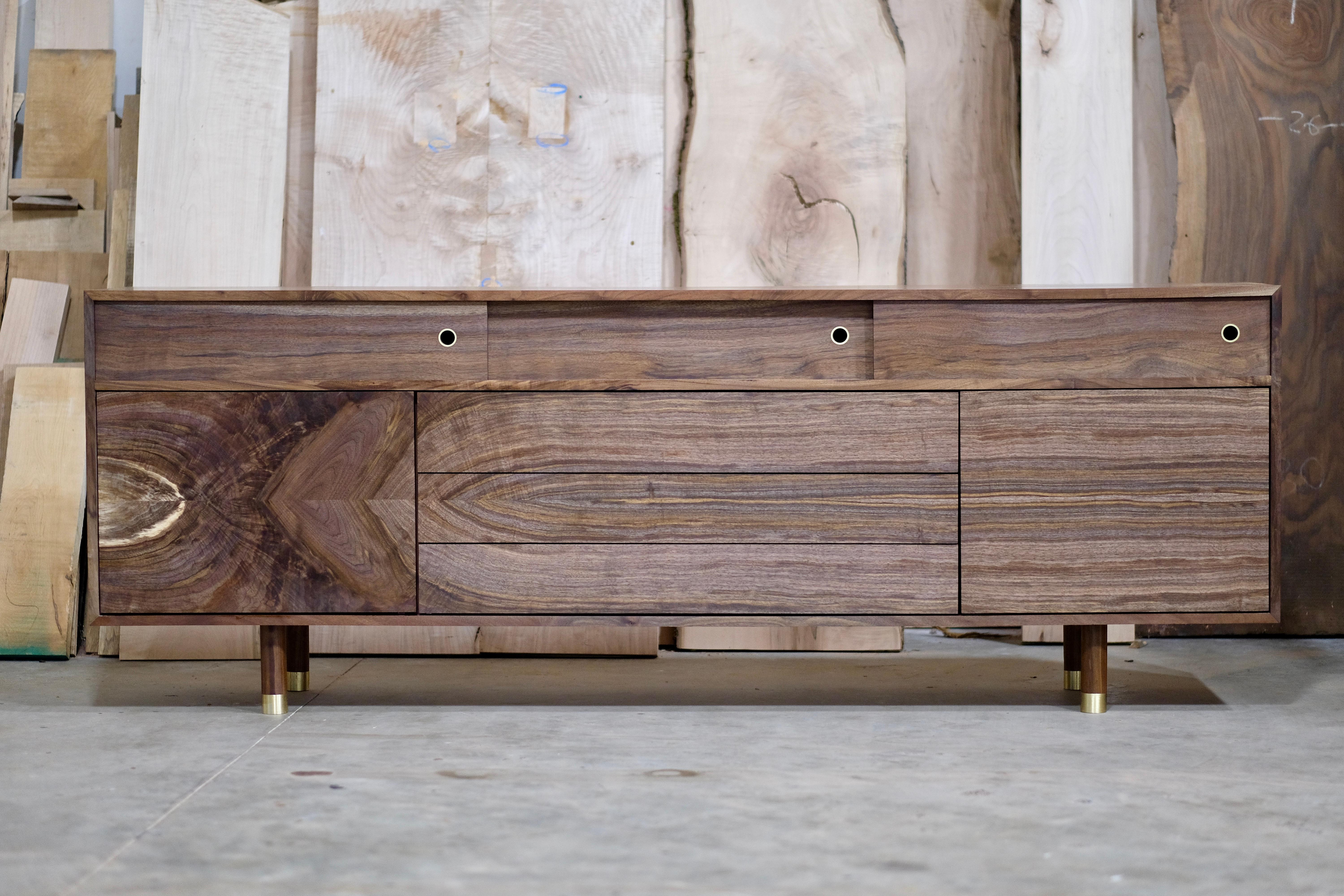 This is a piece that truly speaks for itself. The fully grain matched solid wood walnut facade brings warmth and depth to this otherwise very simple silhouette. The custom made brass feet and drawer pulls on the sliding doors compliment the walnut