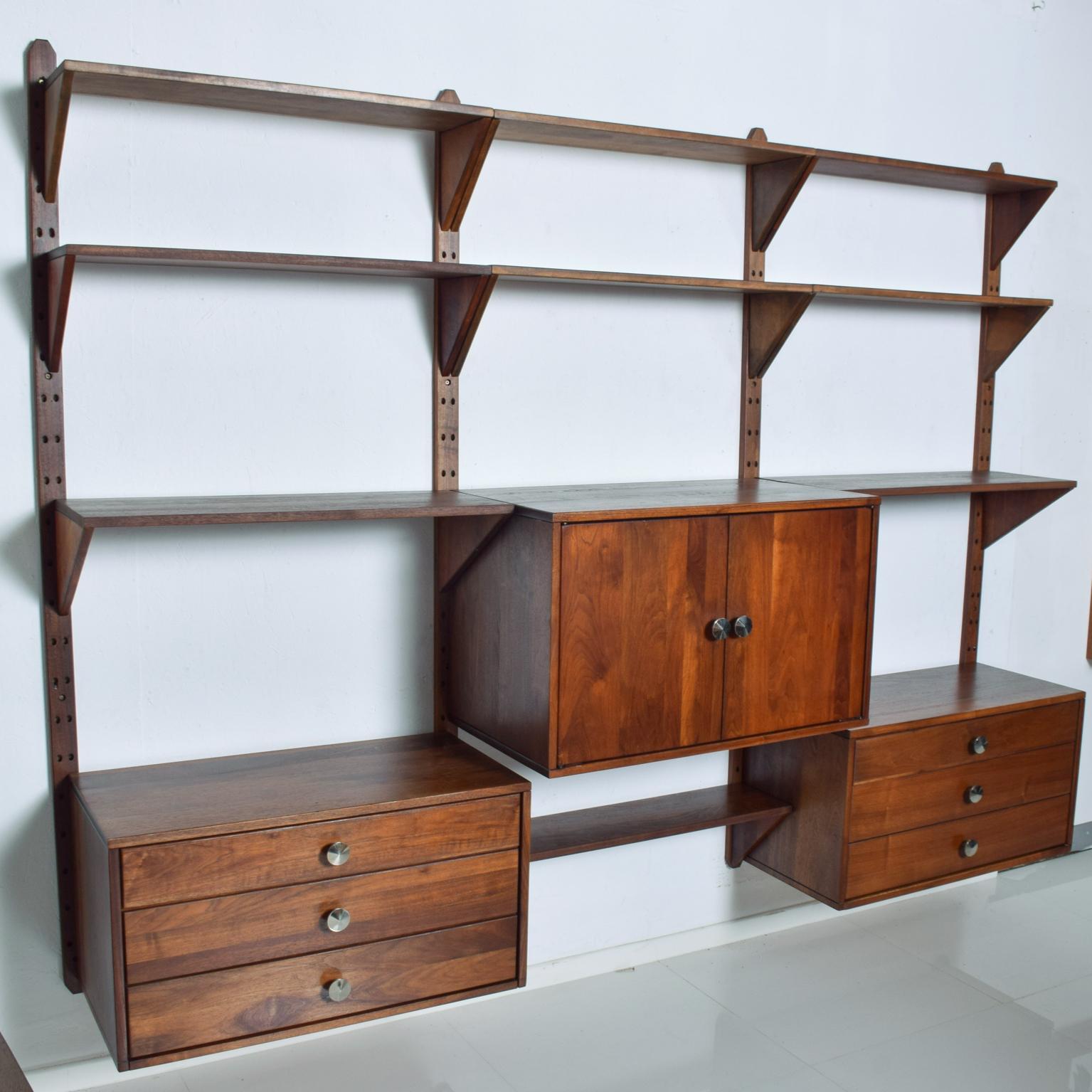 We are pleased to offer for your consideration, a beautiful wall unit made in Solid Walnut wood. 3 Bay system similar to CADO construction. No label present from the maker. One large storage cabinet with shelf and two cabinets with pull out drawers.